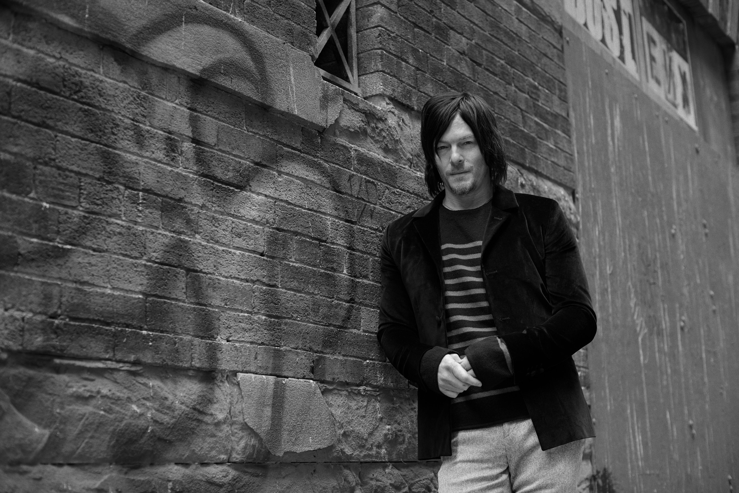 Norman Reedus leaning against a brick wall HD Wallpaper