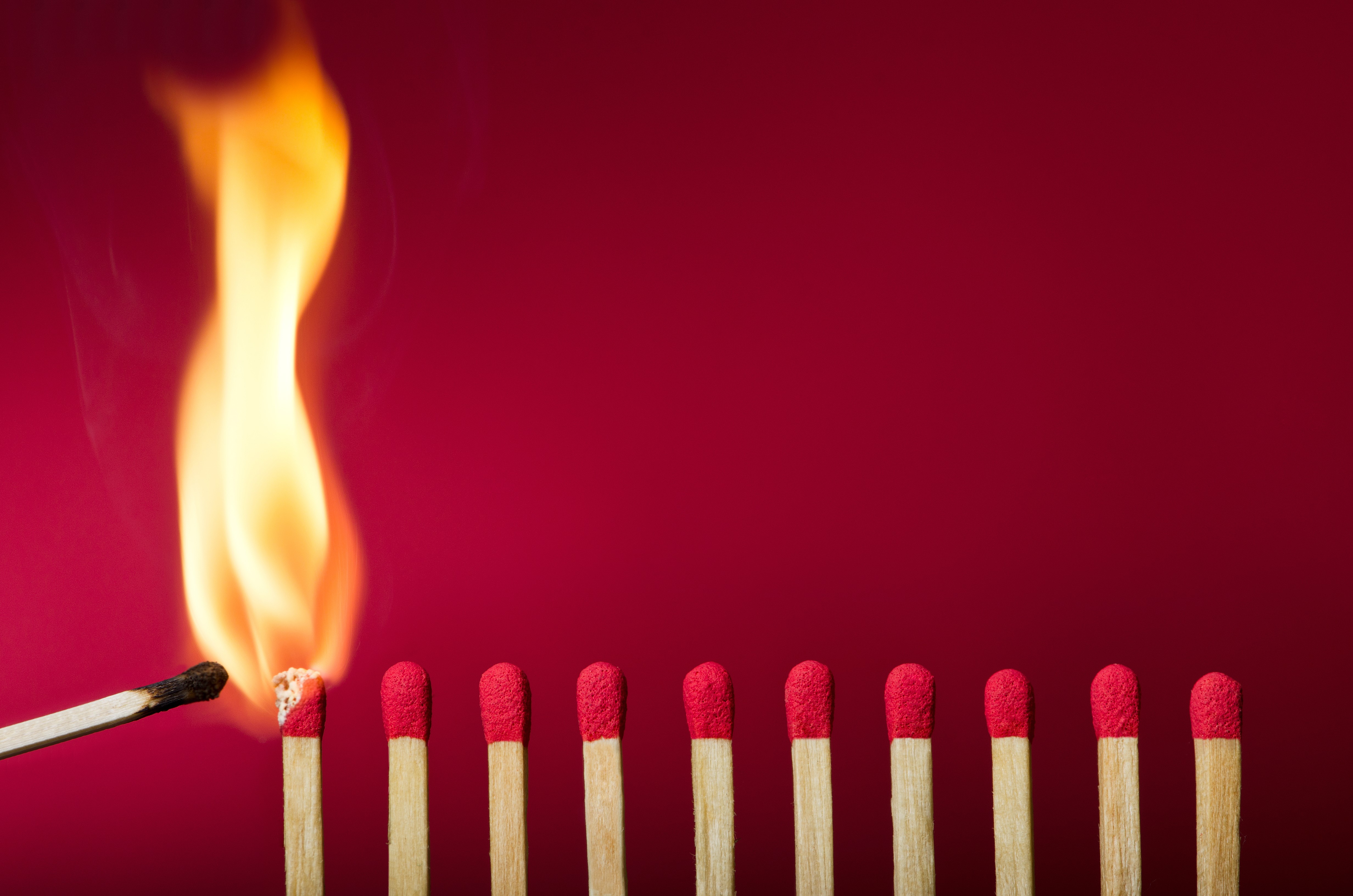 Burning match igniting others on red background HD Wallpaper