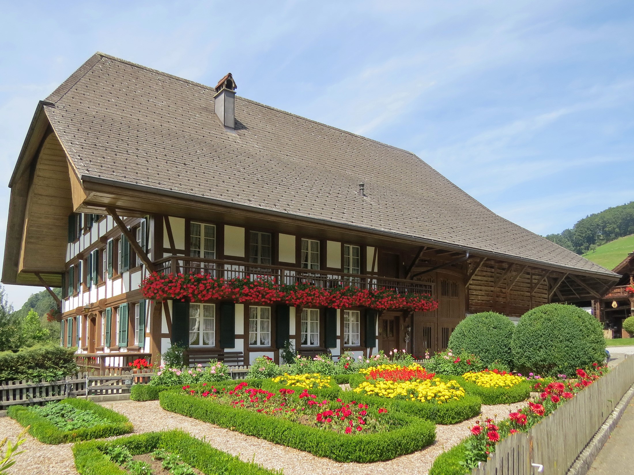 Traditional Swiss farmhouse with flower garden in Lutzelfluh, Switzerland HD Wallpaper