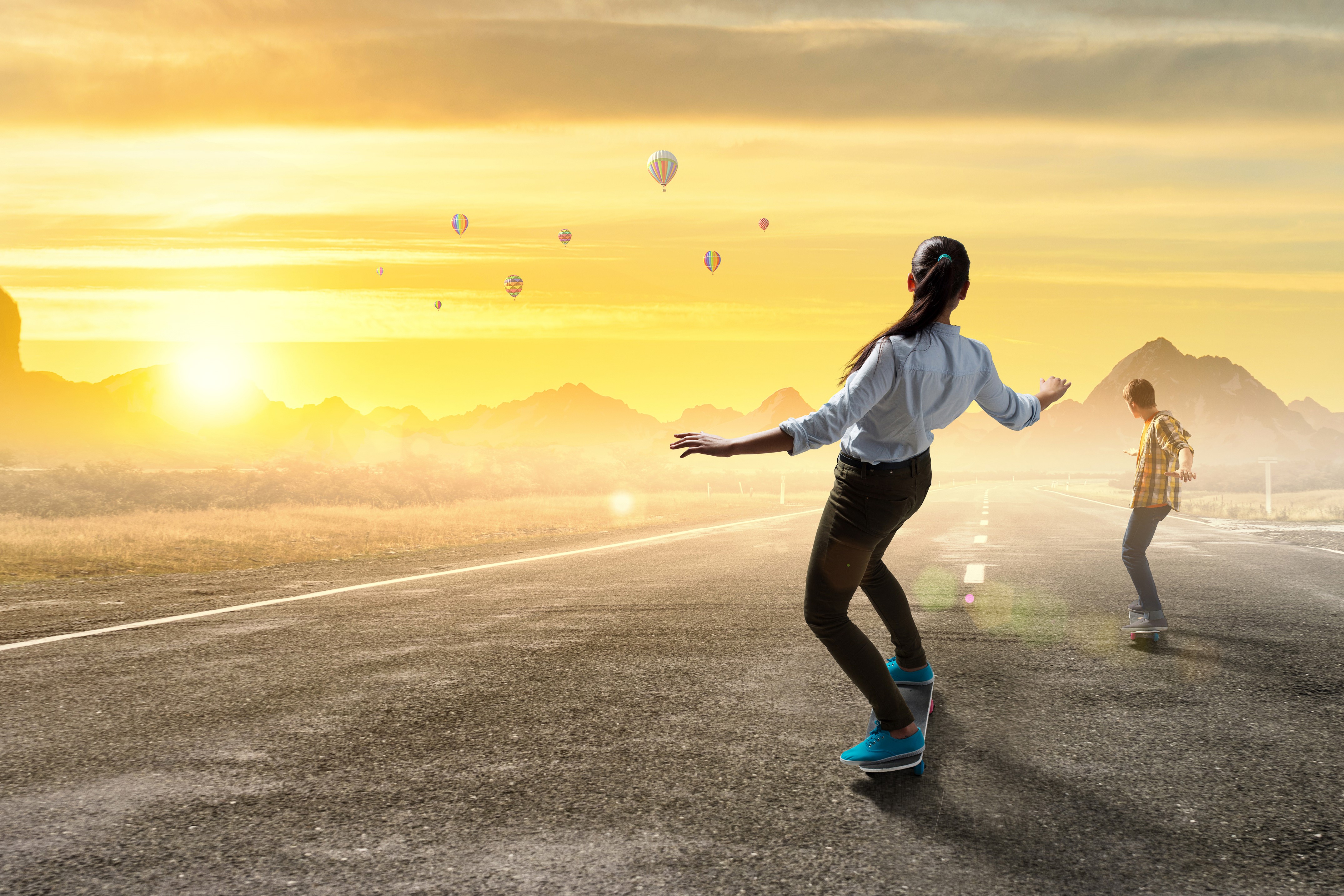 Two people skateboarding on a road with hot air balloons HD Wallpaper