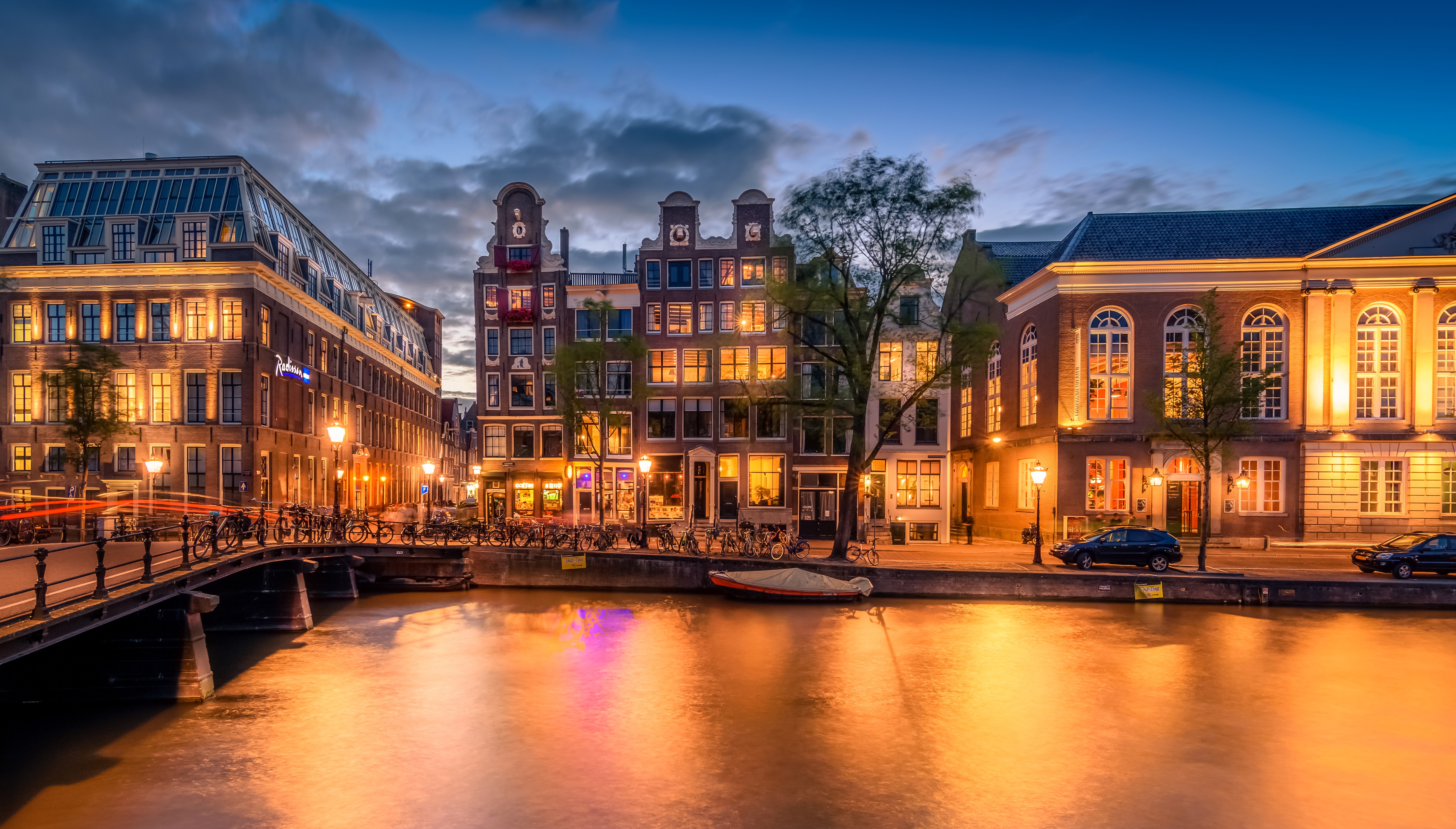 Amsterdam canal at dusk with bridges and buildings HD Wallpaper