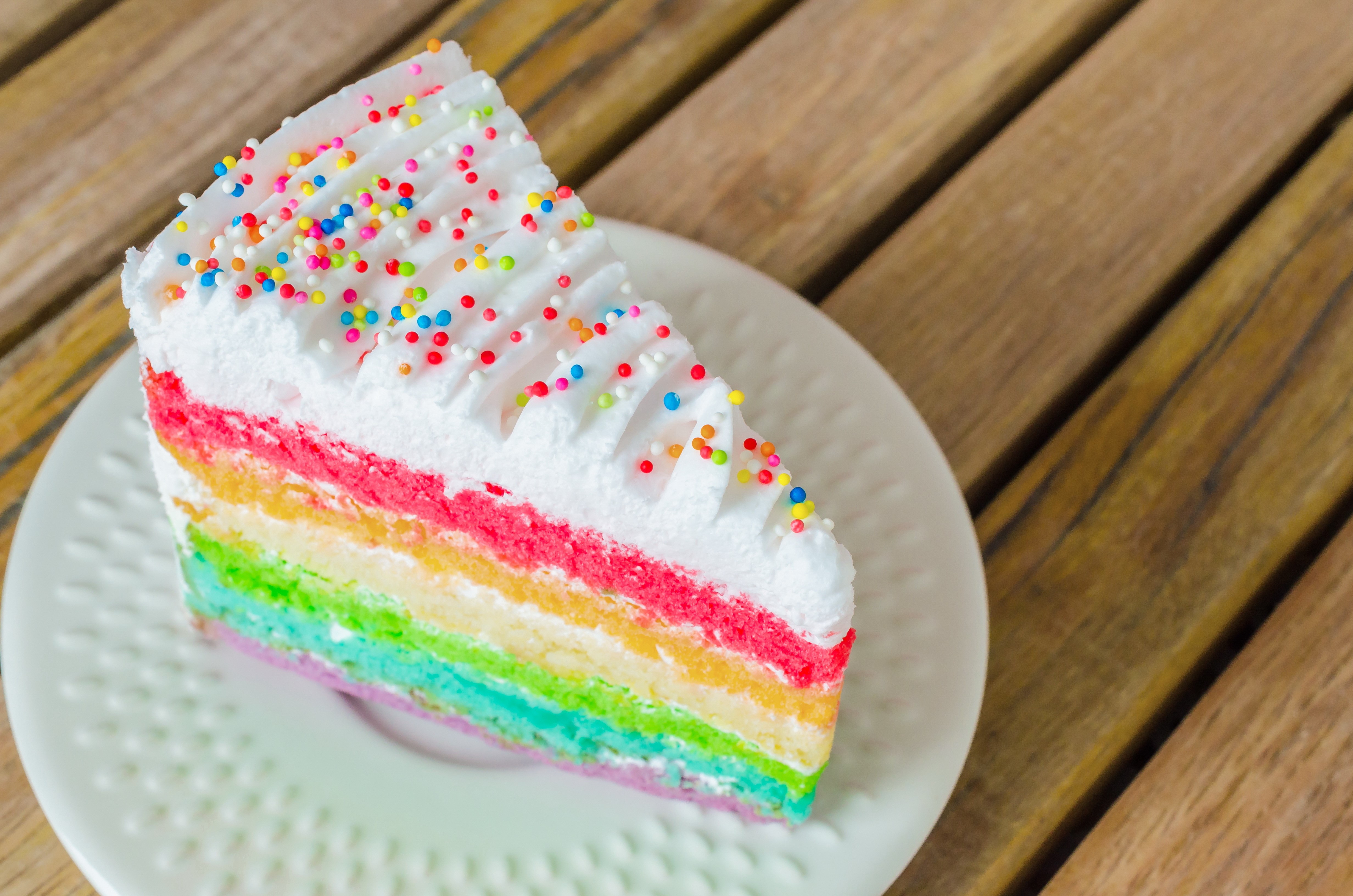 Slice of rainbow cake with sprinkles on a saucer HD Wallpaper