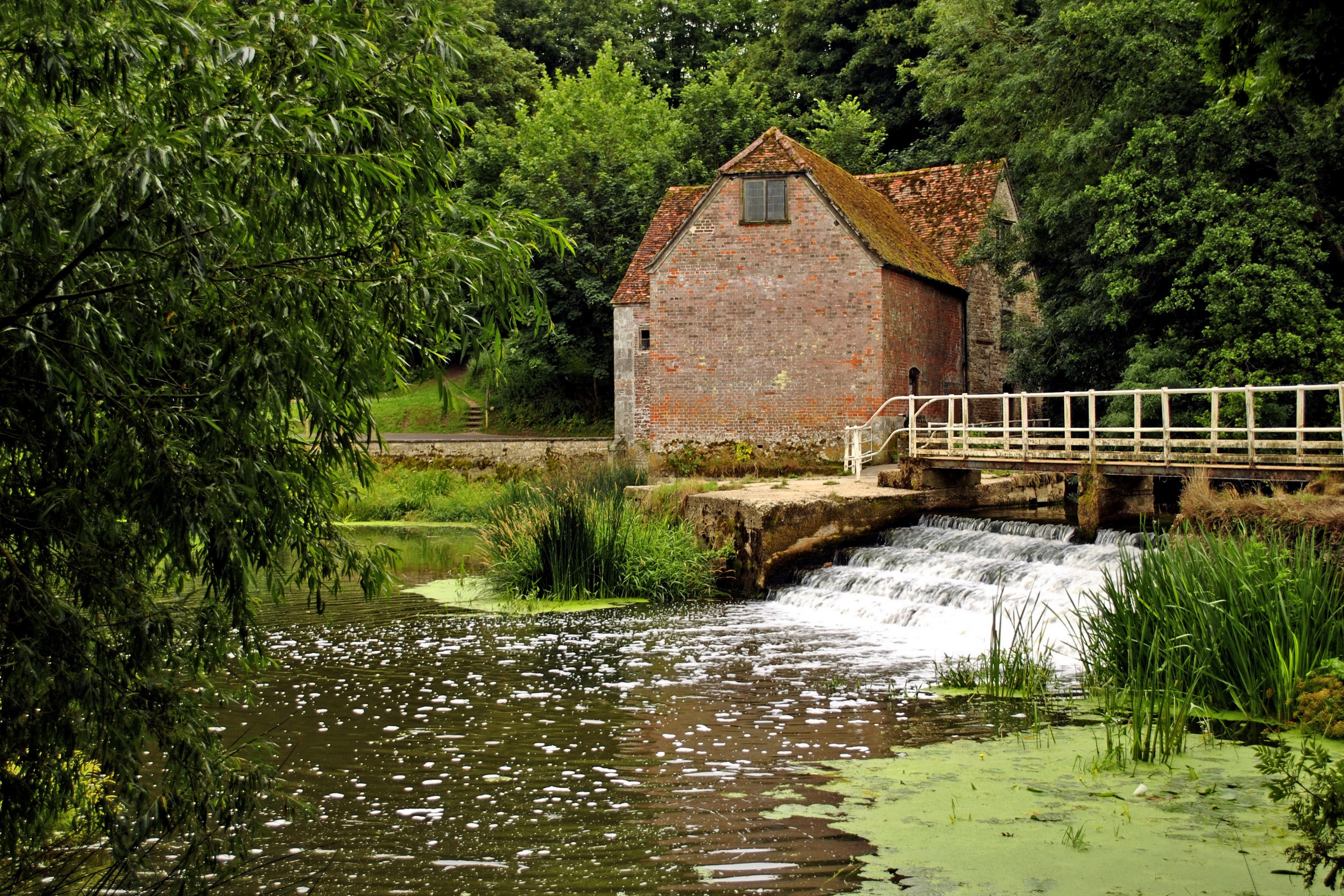Old brick mill building with a waterfall and bridge in England HD Wallpaper