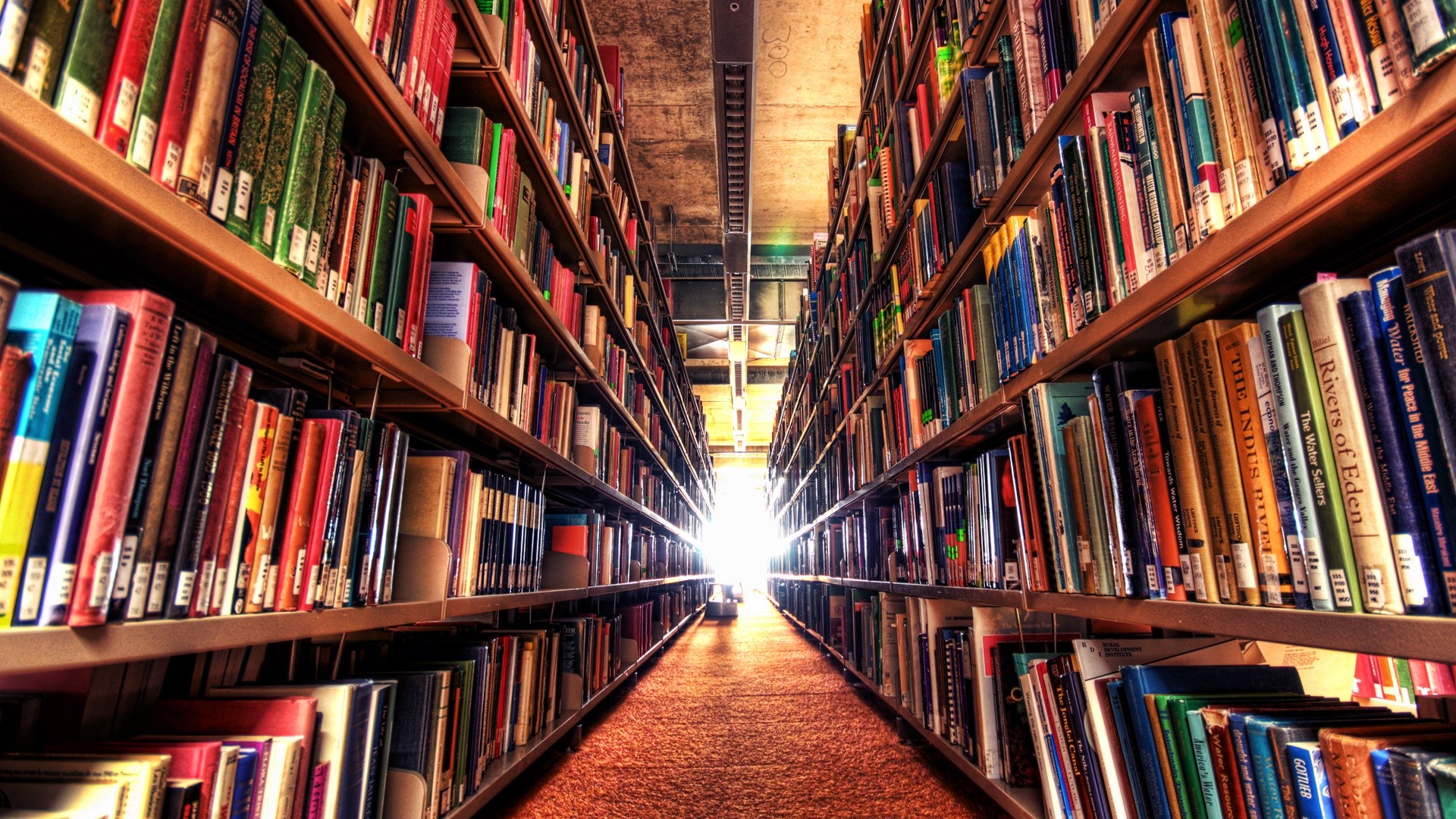Library aisle with bookshelves full of books HD Wallpaper