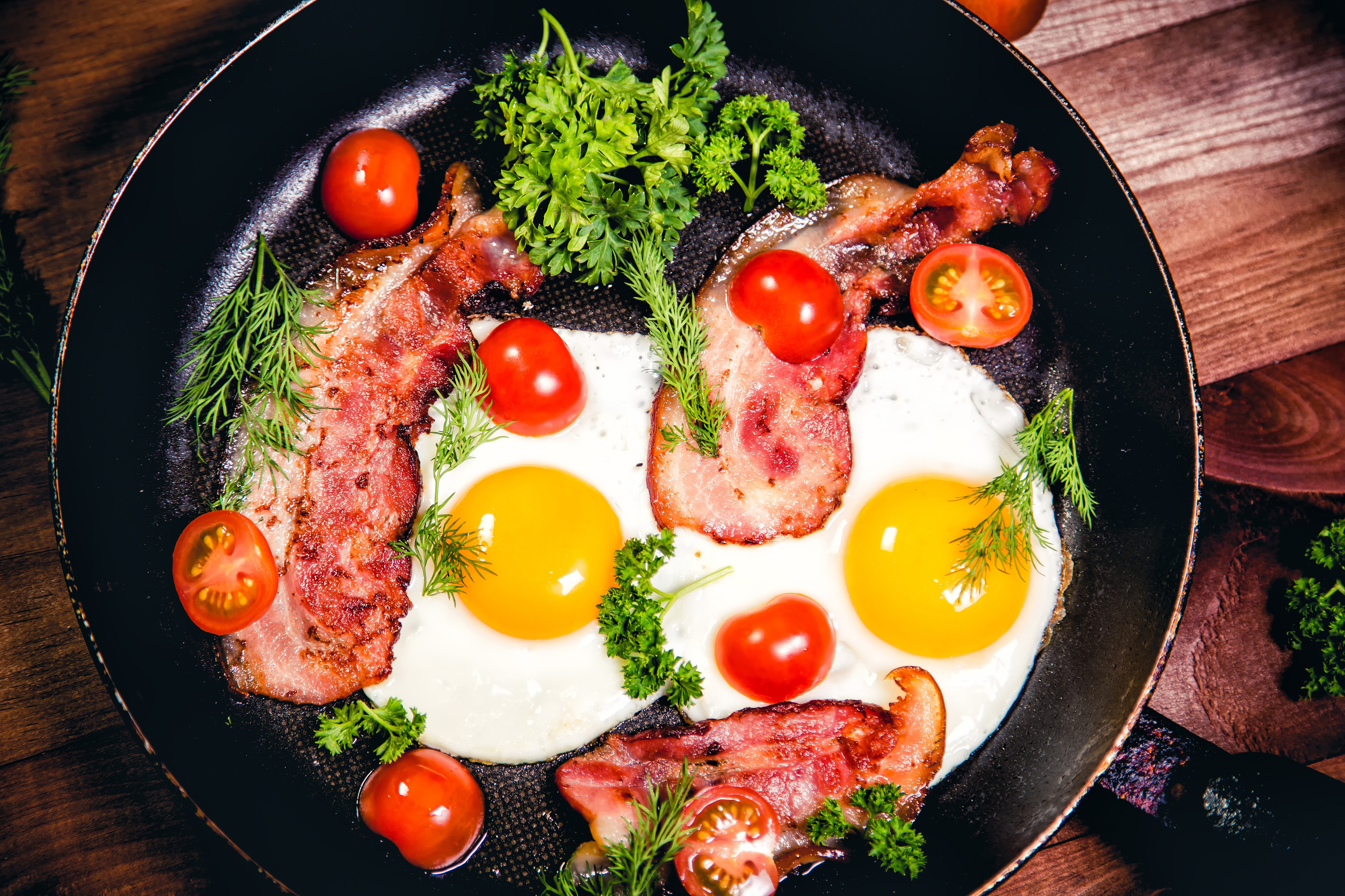 Fried eggs with bacon, tomatoes, and dill in a frying pan HD Wallpaper