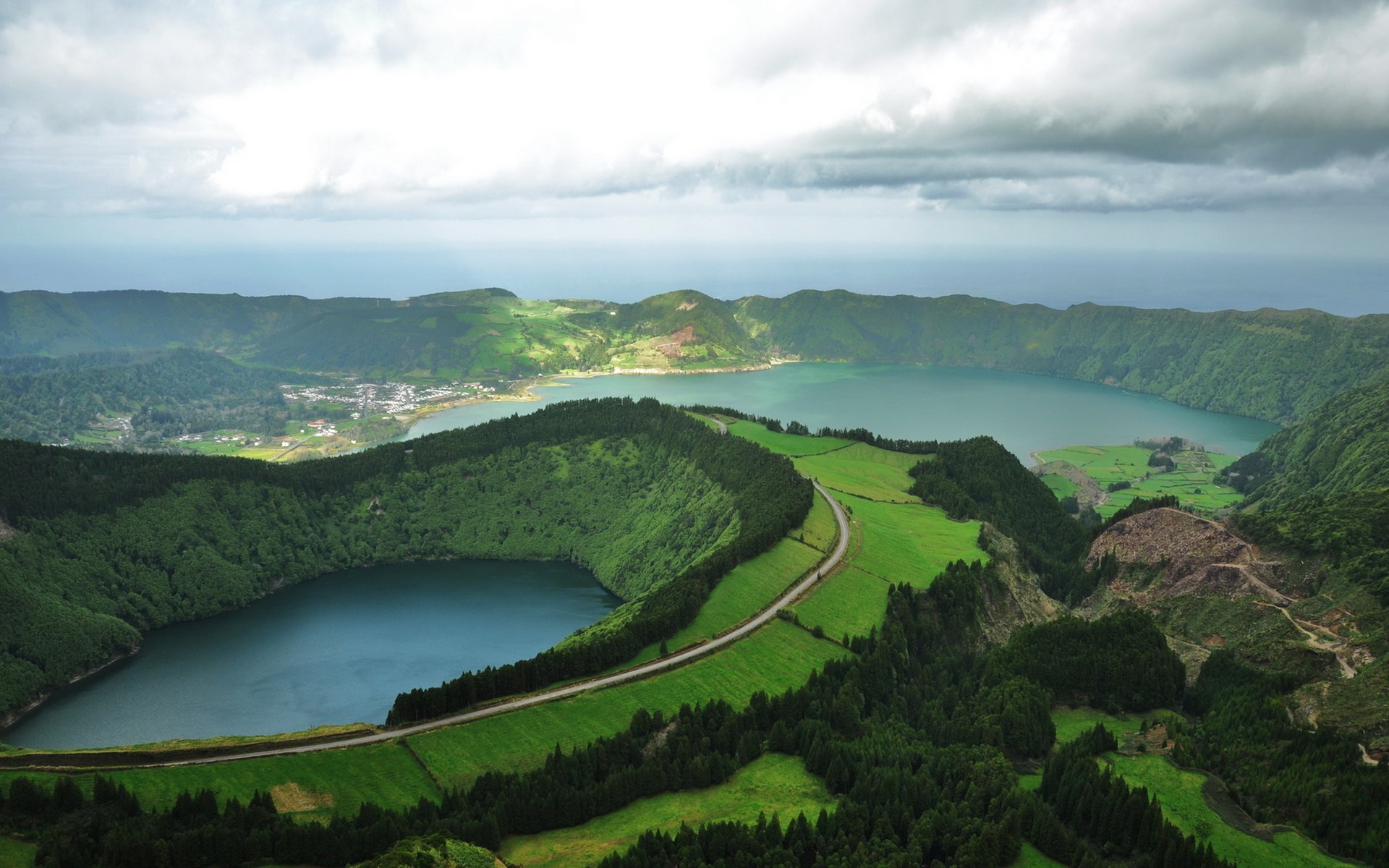 Volcanic crater lakes with green hills and a road HD Wallpaper