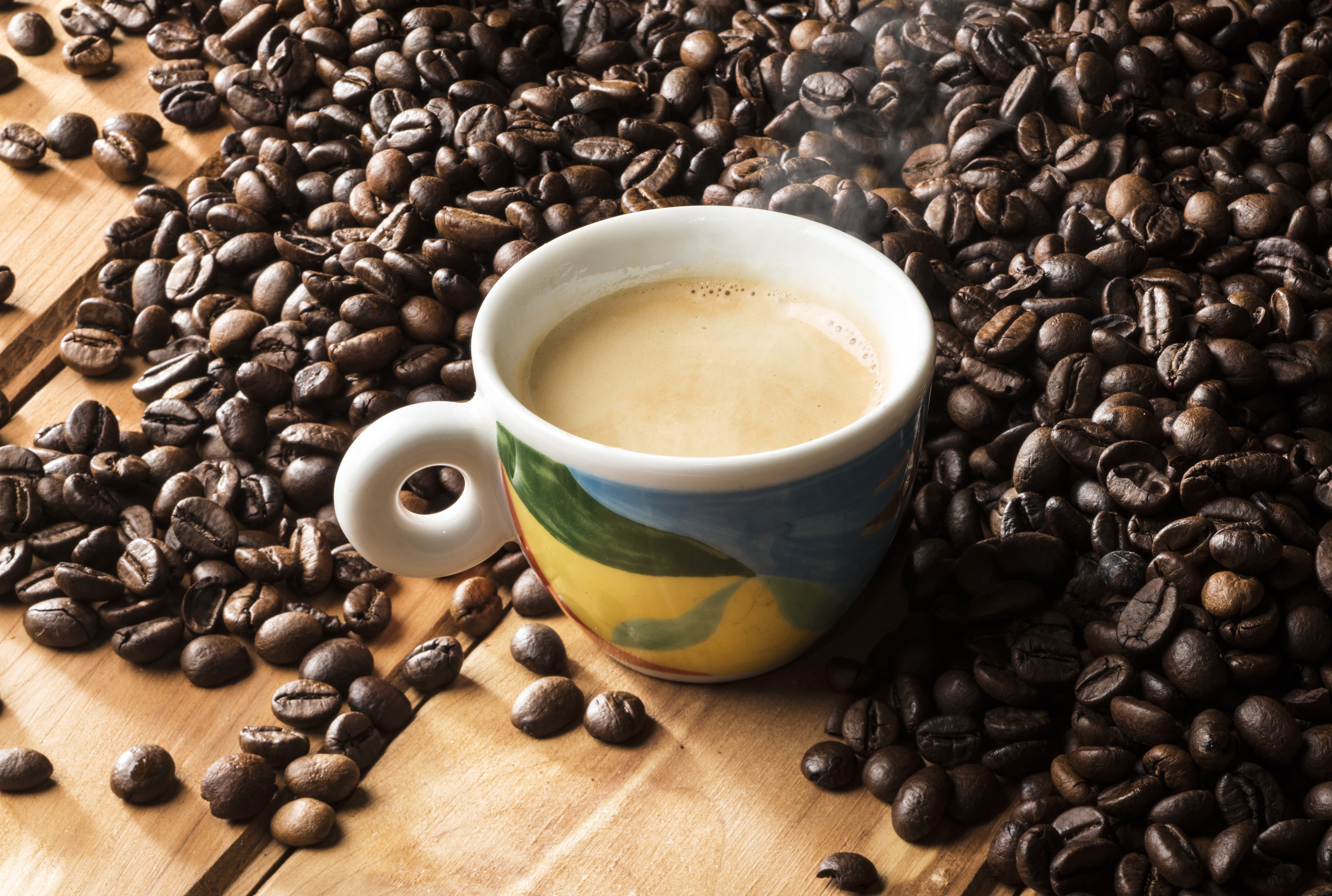 Cup of Coffee surrounded by Coffee Beans HD Wallpaper