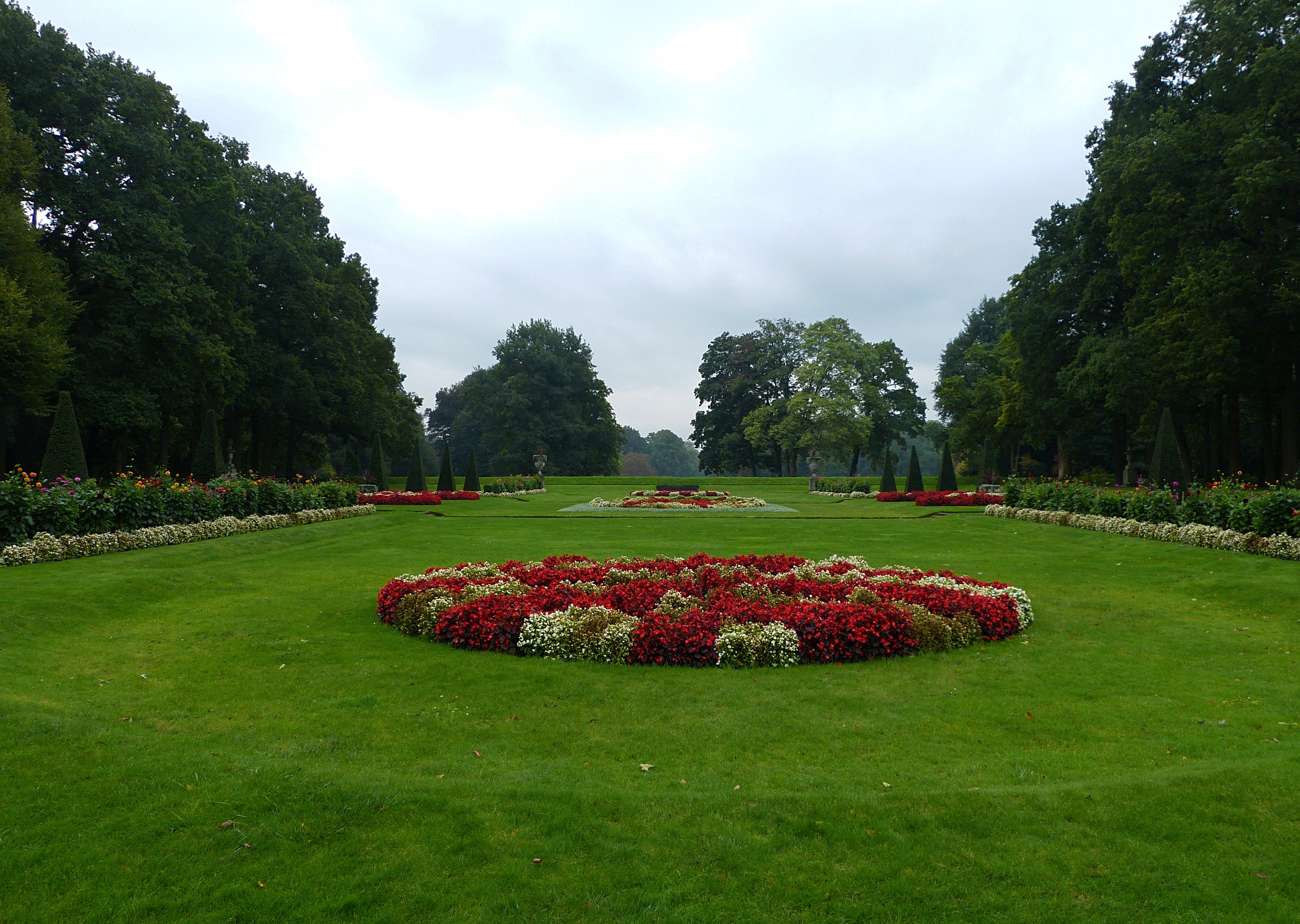 Formal garden with flower beds and manicured trees HD Wallpaper