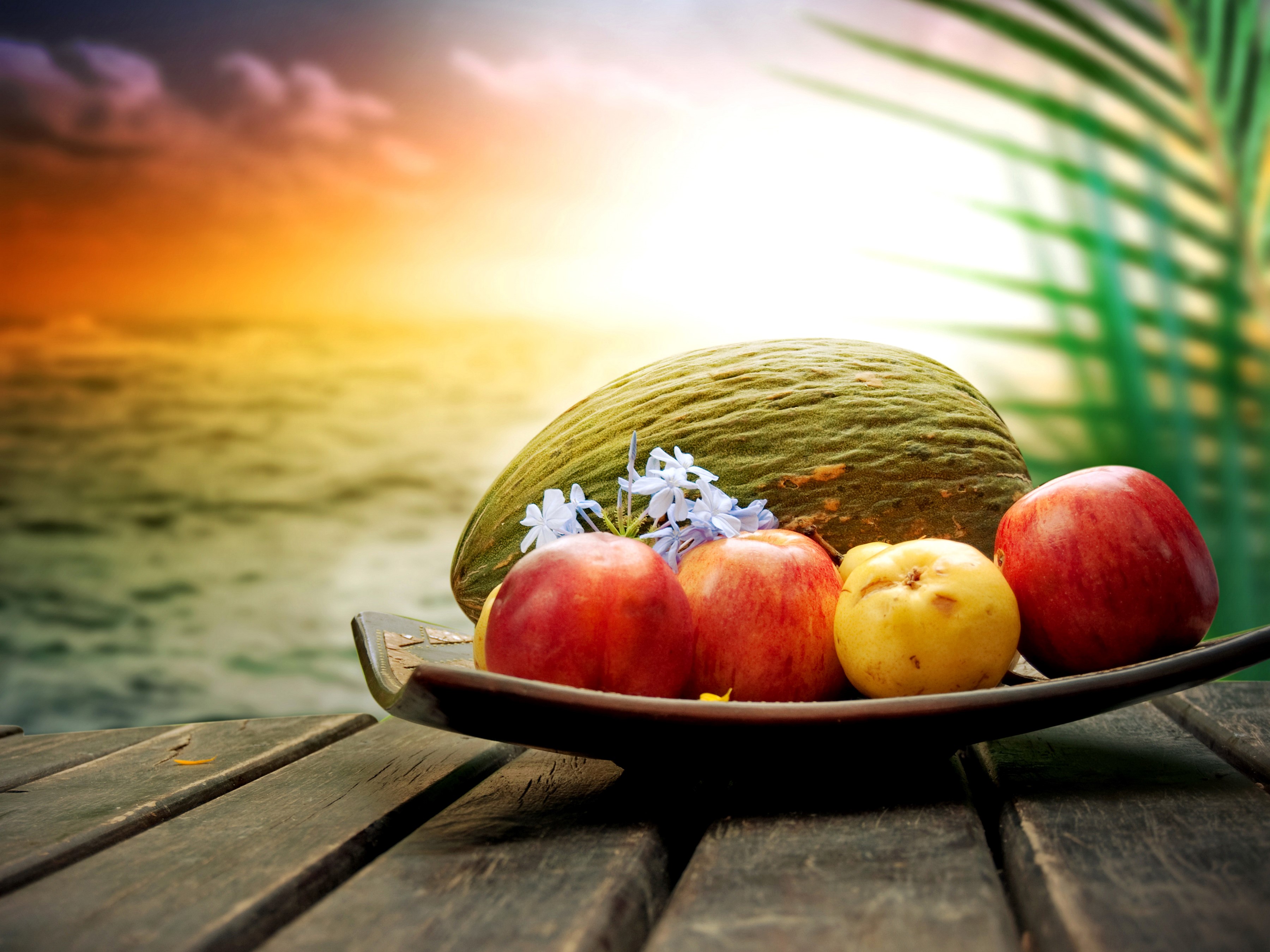 Fruit bowl with apples and melon on a wooden table at sunset HD Wallpaper