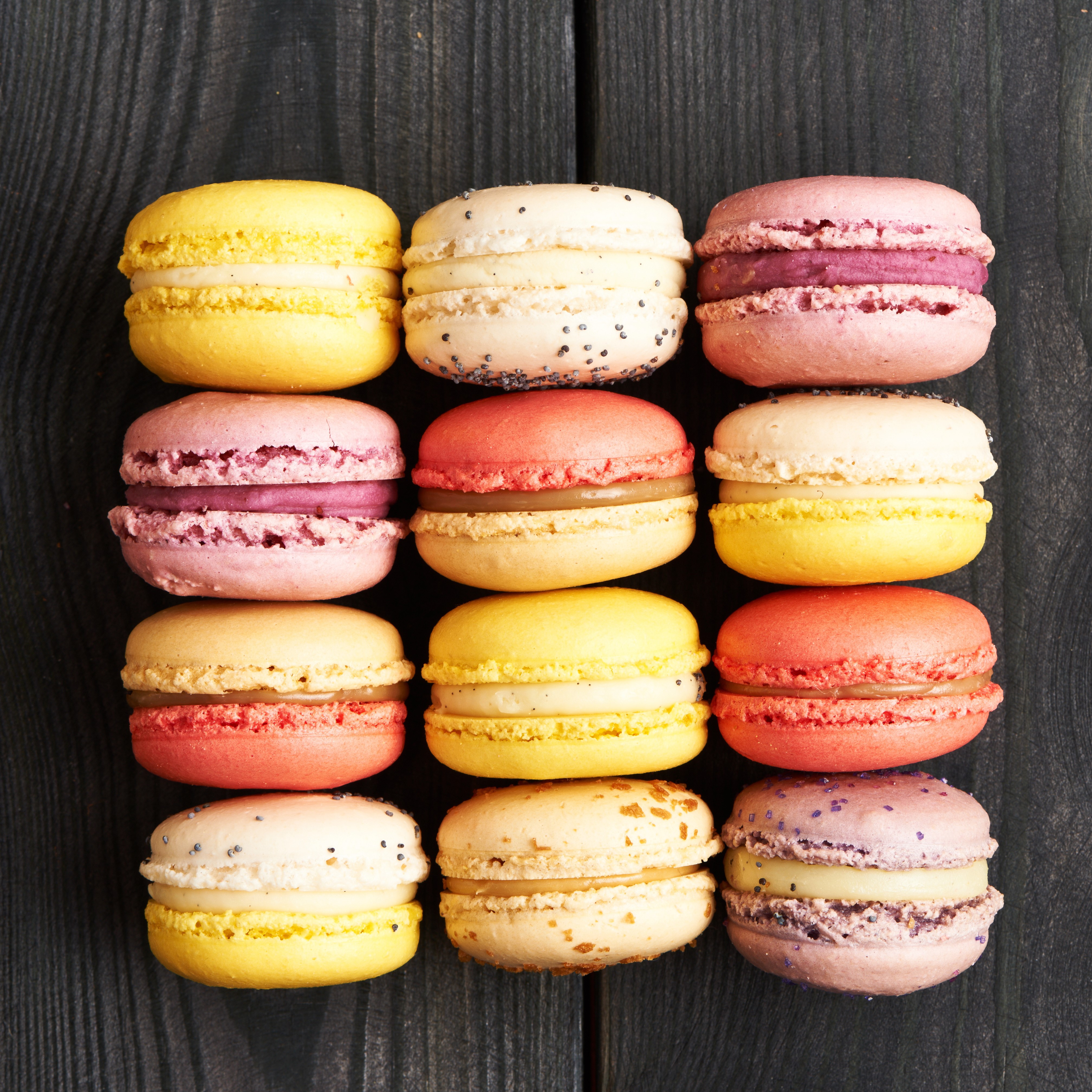 Assortment of colorful macarons on a dark wooden surface HD Wallpaper