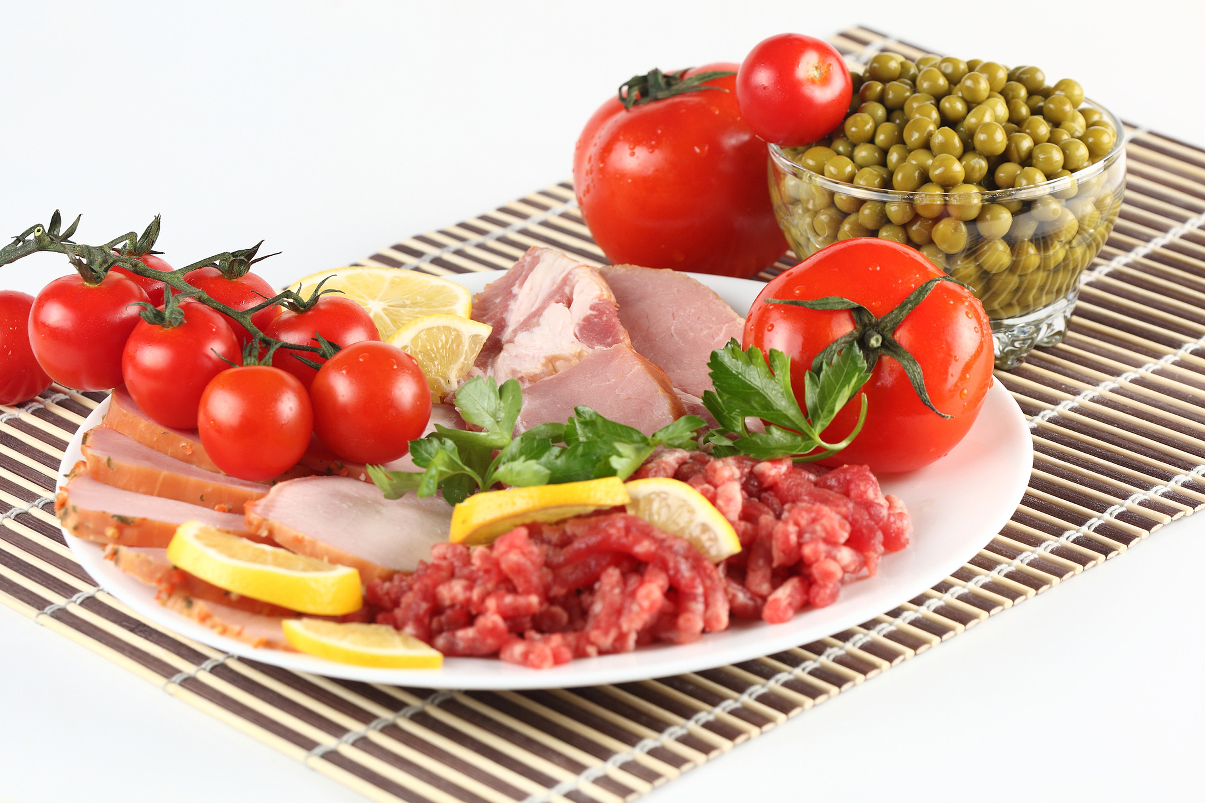 Meat products, tomatoes, green peas, and lemon on a plate HD Wallpaper