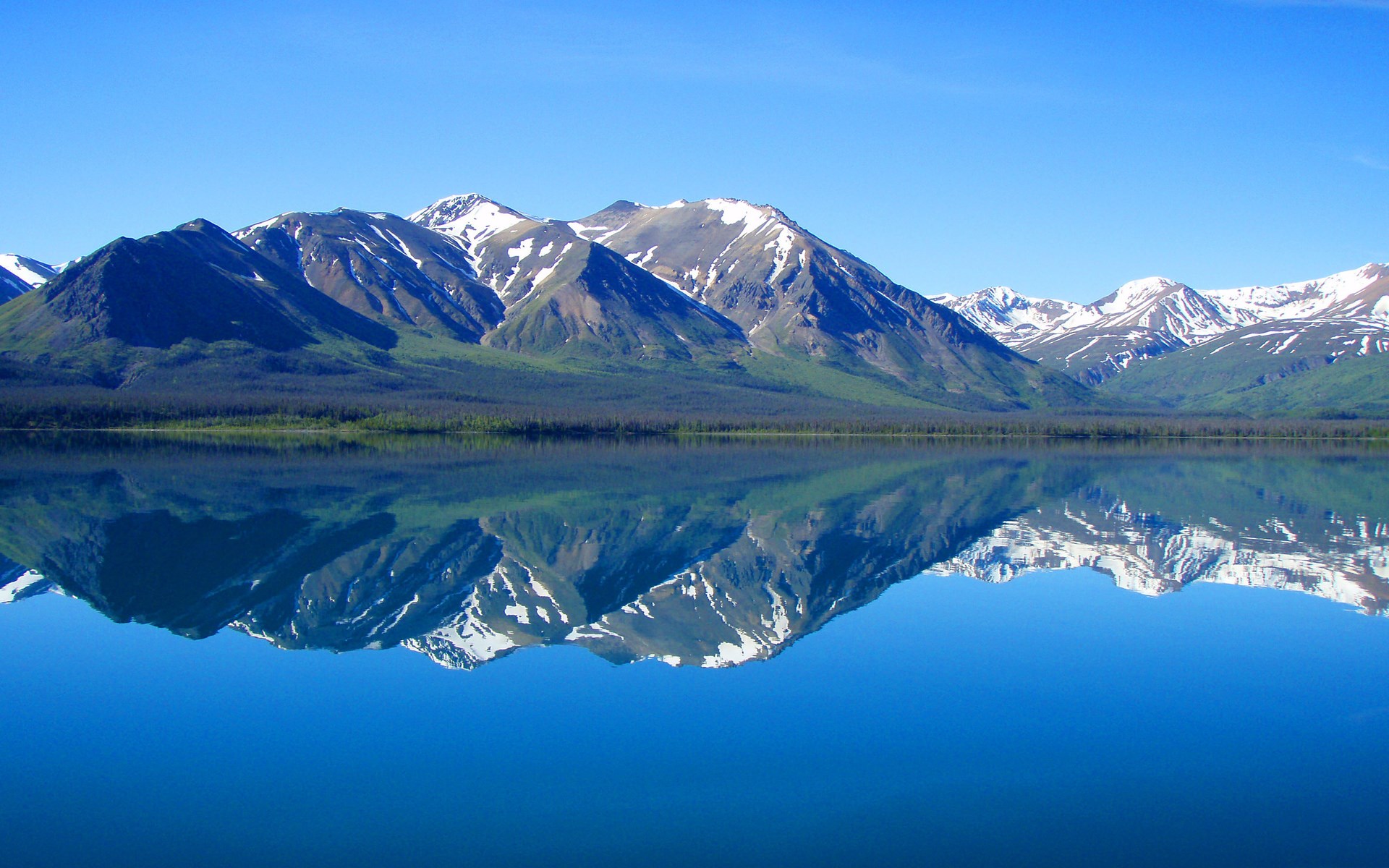 Snow-capped mountains reflected in a calm lake HD Wallpaper