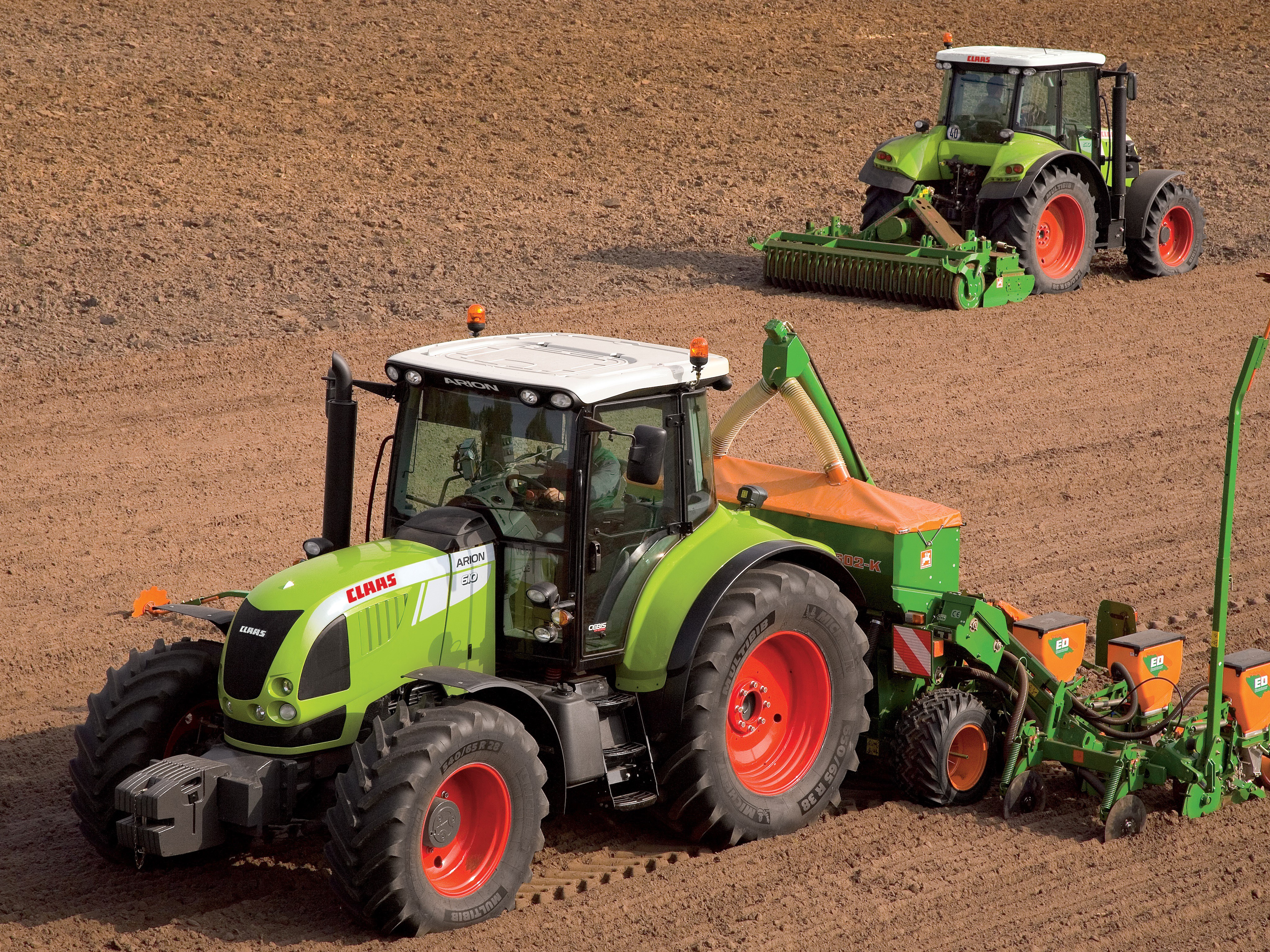 Two Claas tractors working in a field HD Wallpaper