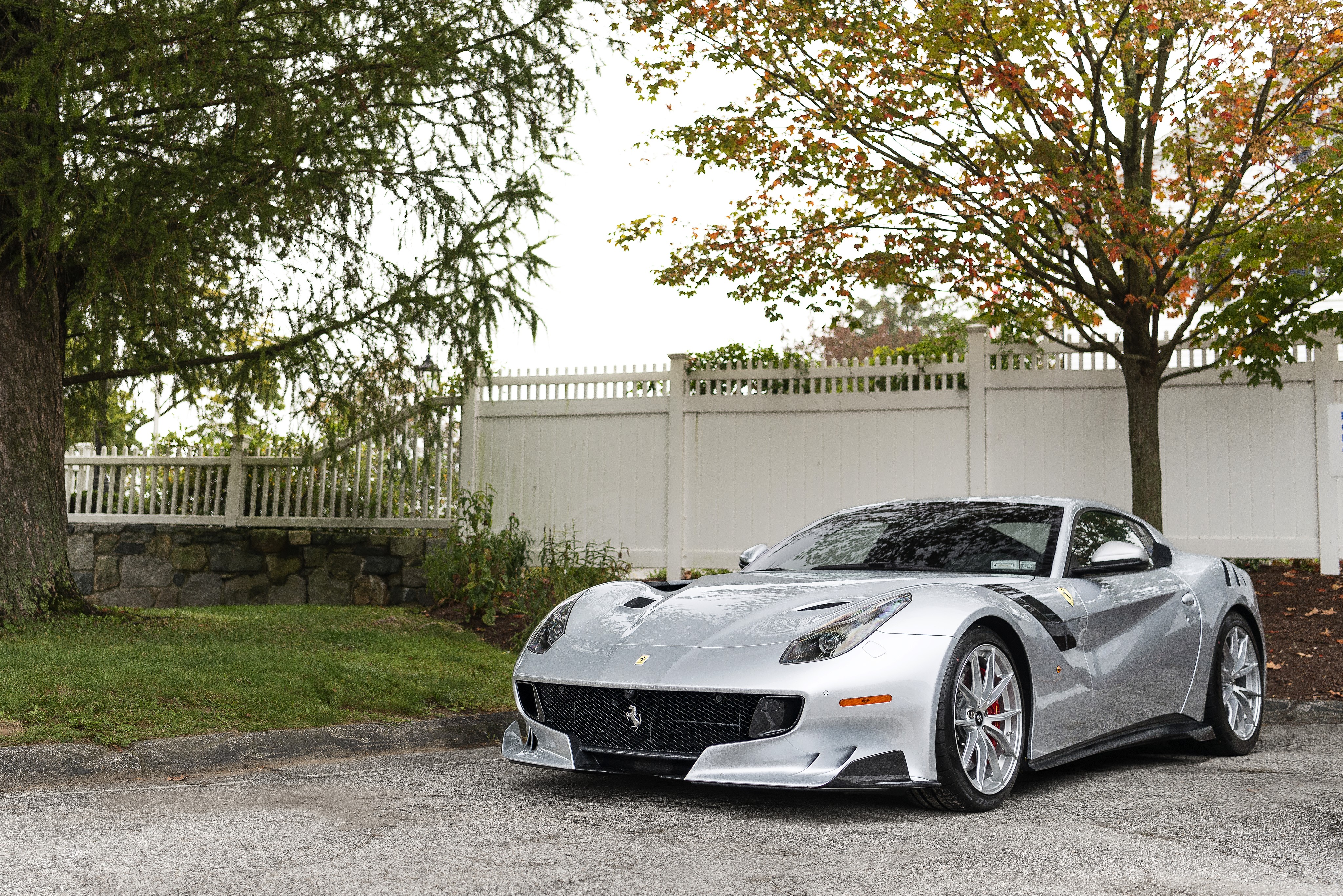 Grey Ferrari F12tdf parked near a white fence HD Wallpaper