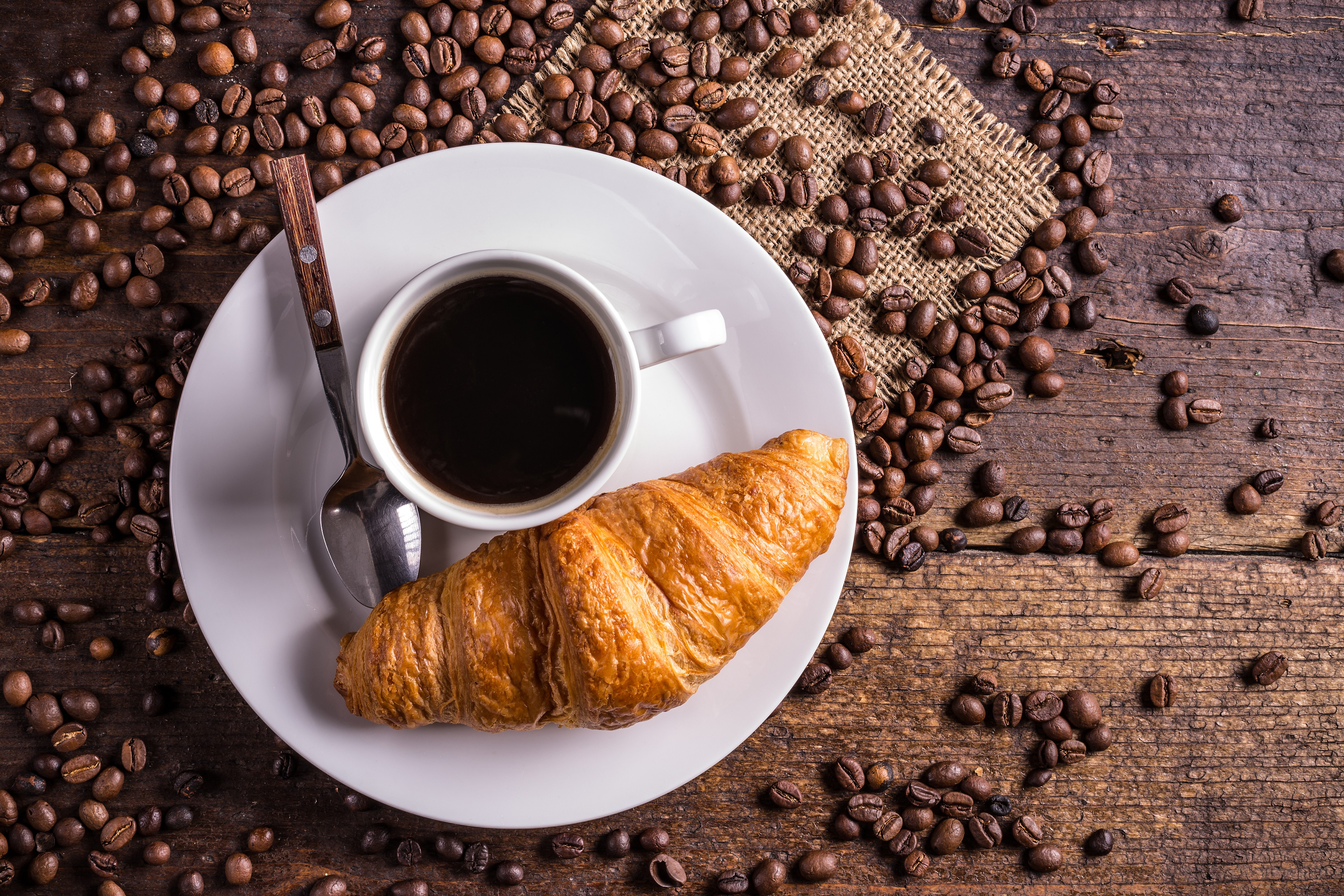 Coffee cup and croissant on a plate with coffee beans HD Wallpaper