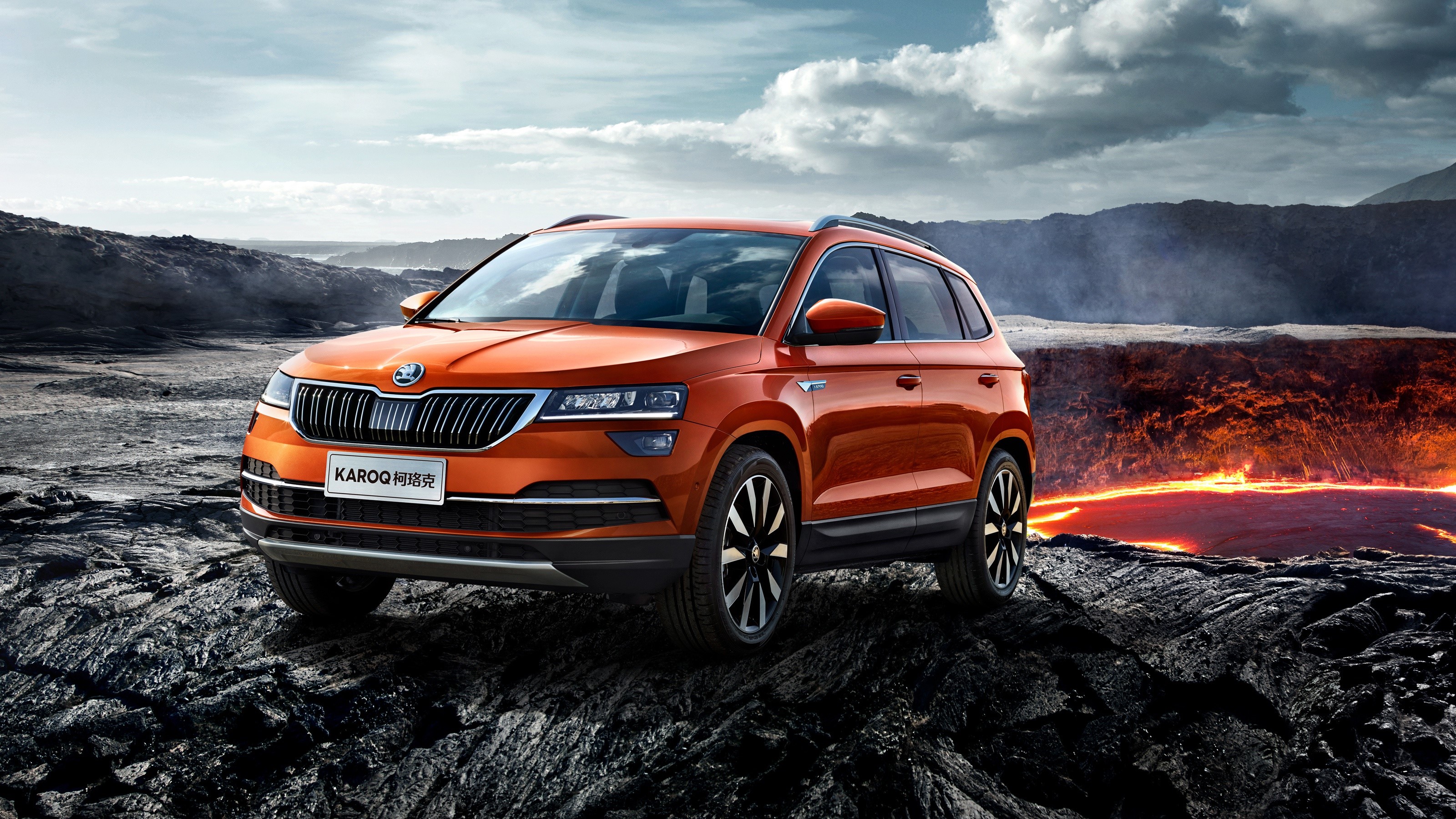 Orange Skoda Karoq SUV on rocky terrain near lava HD Wallpaper