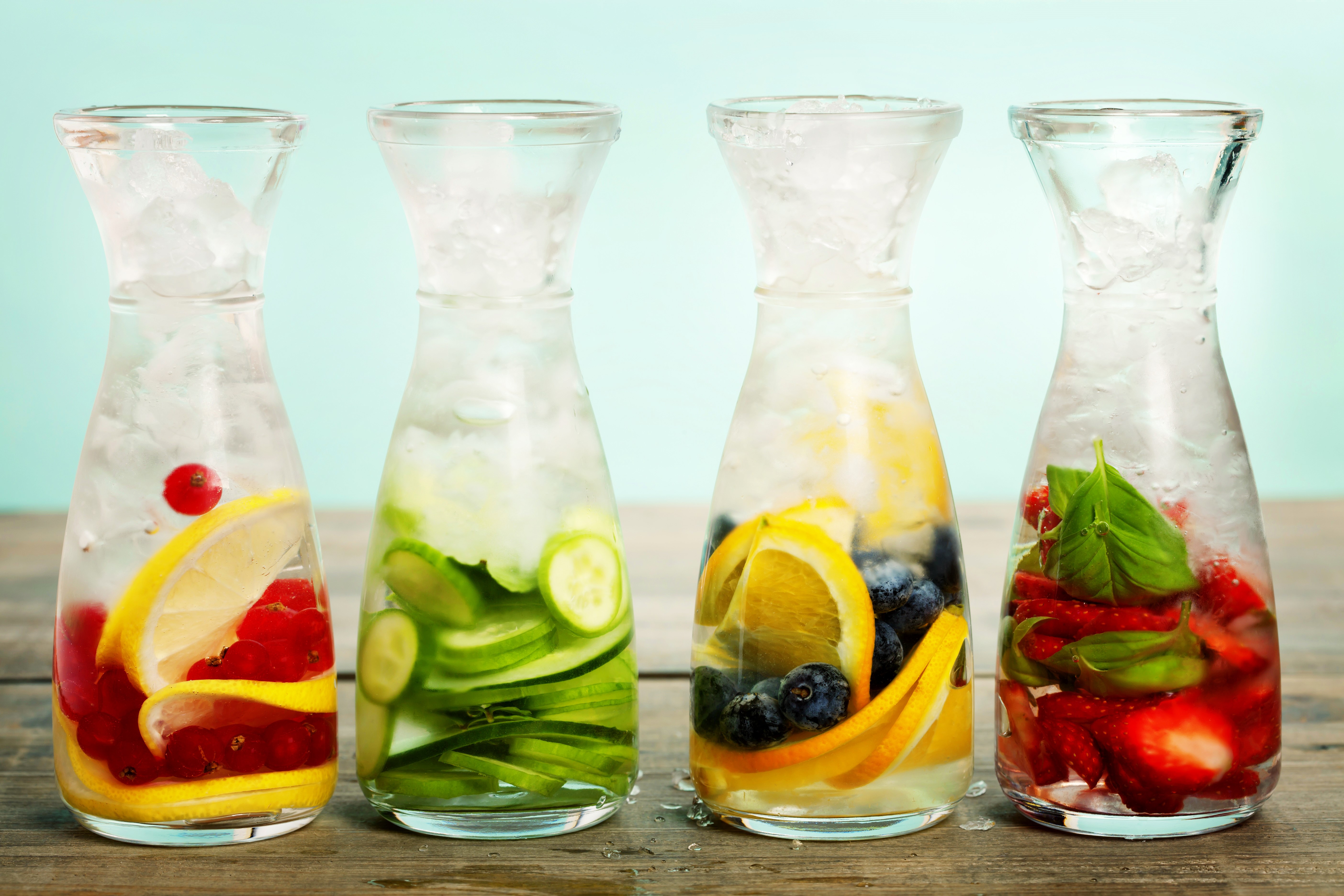 Four glass bottles with infused water and ice HD Wallpaper