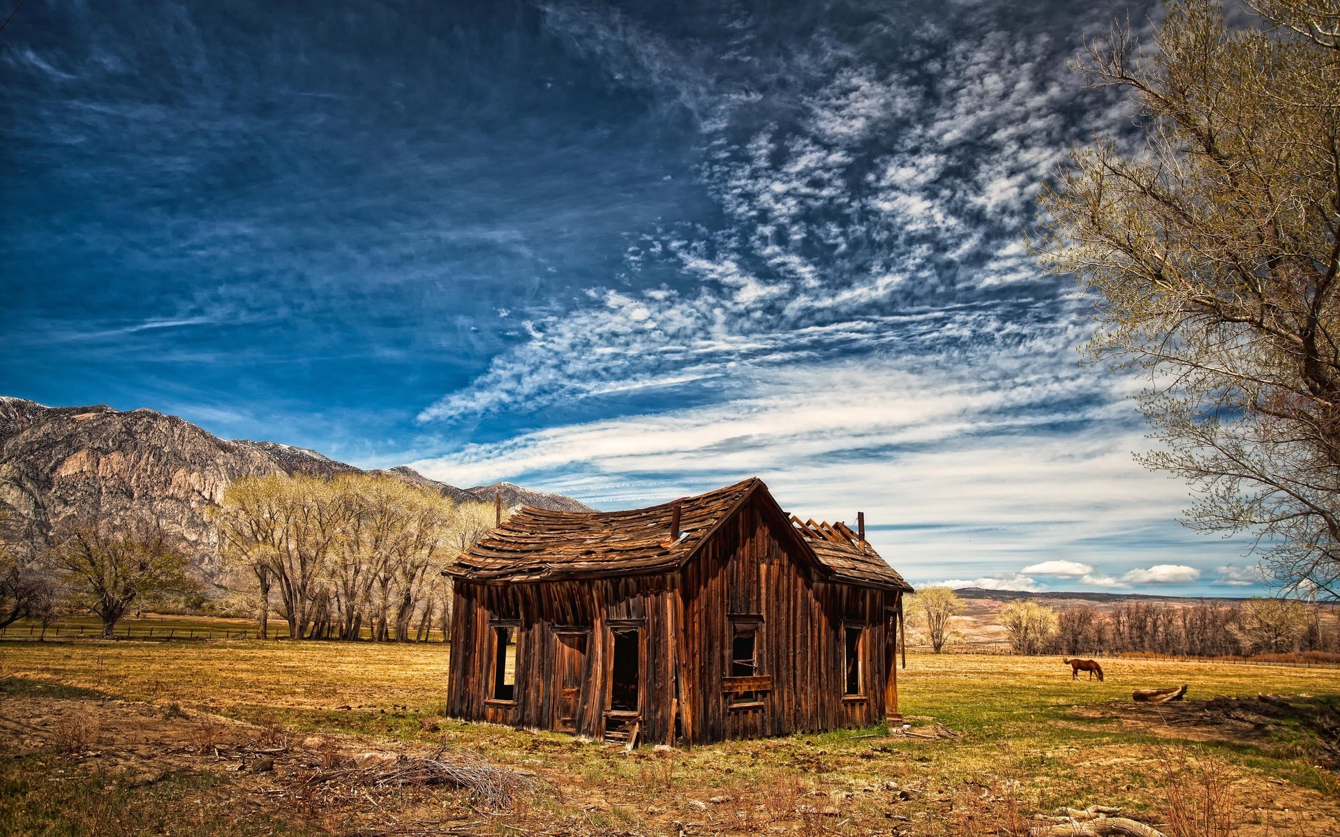 Abandoned wooden house in a field with mountains HD Wallpaper