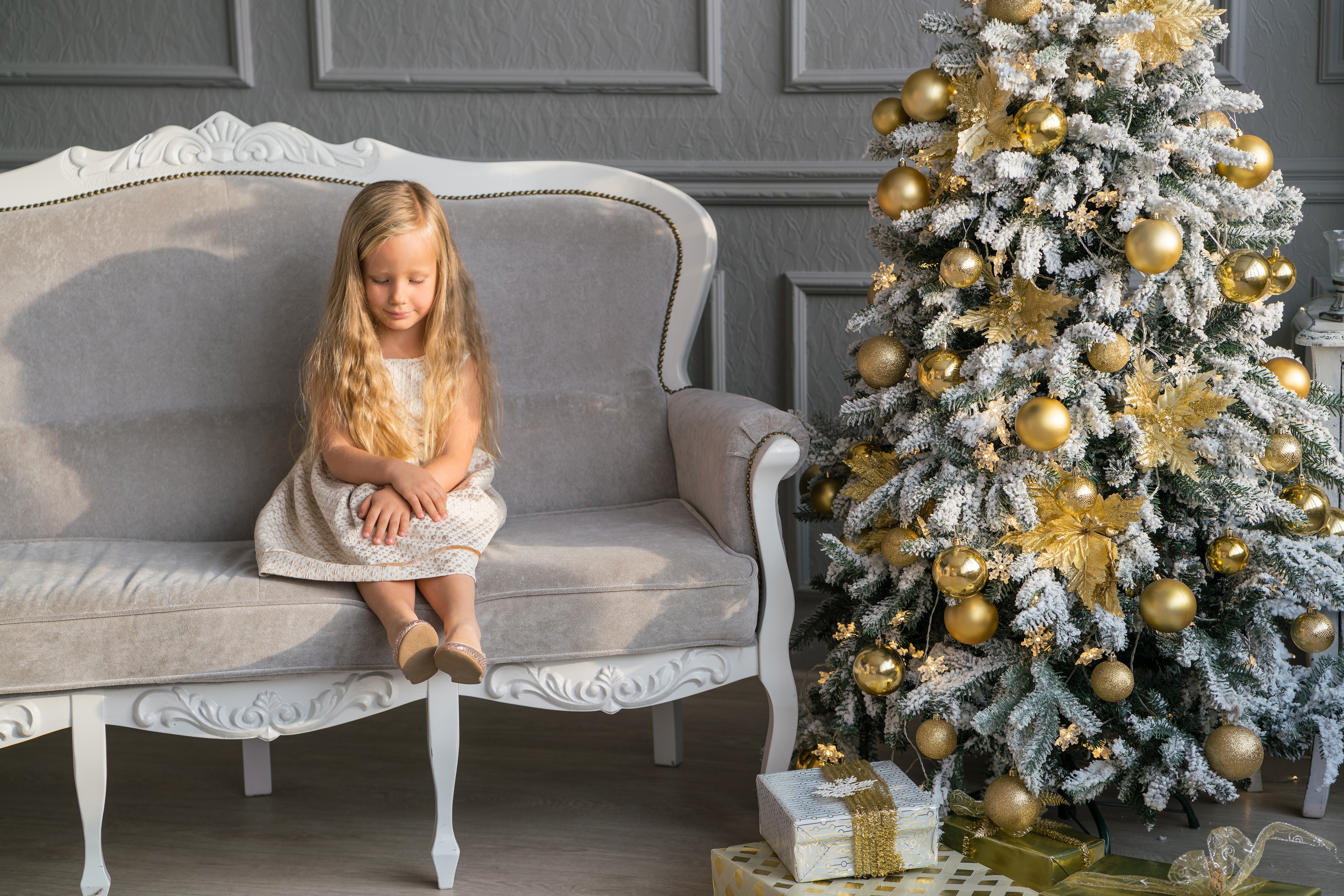 Little girl sitting on a sofa near a Christmas tree HD Wallpaper