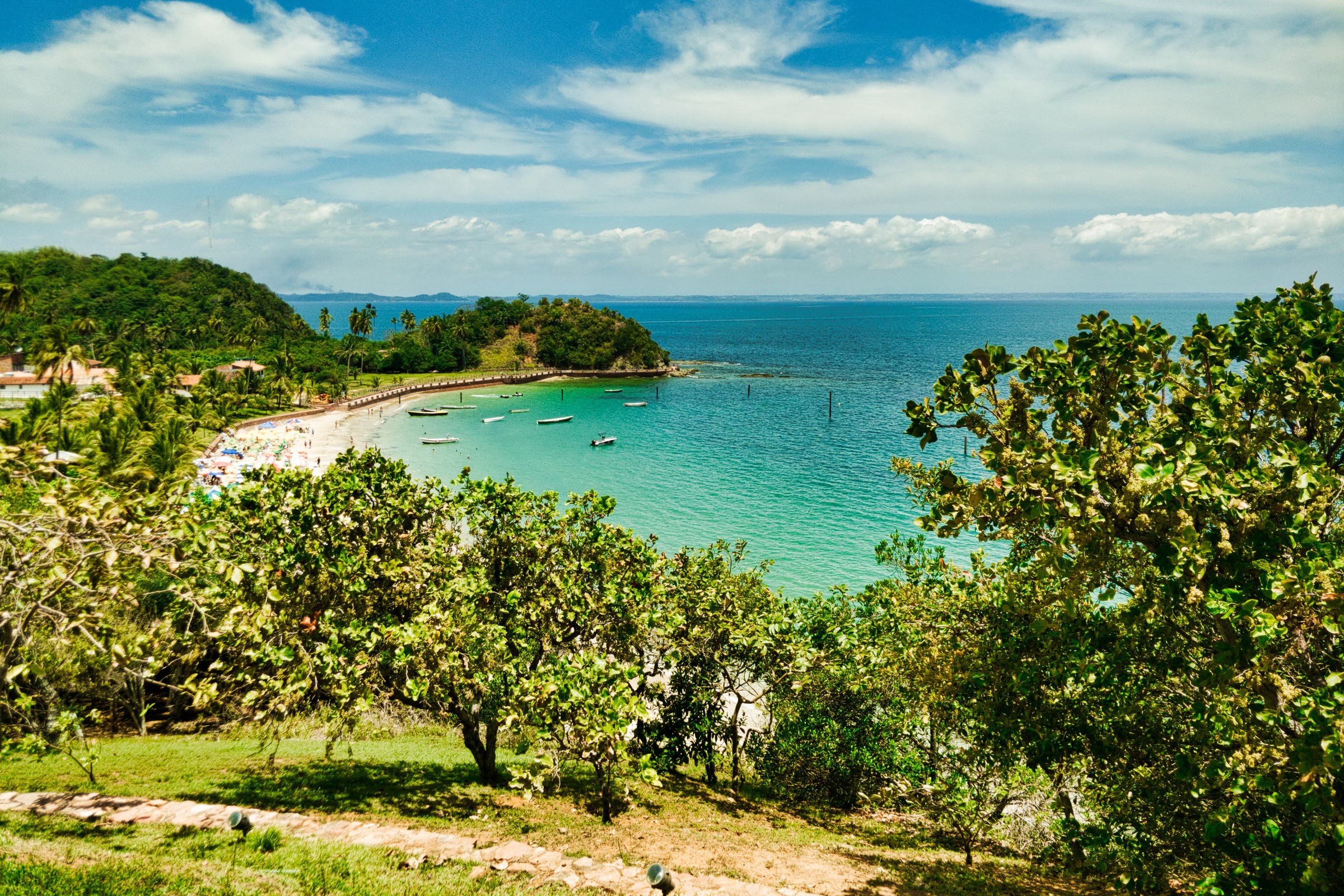 Tropical beach with boats and lush green hills HD Wallpaper