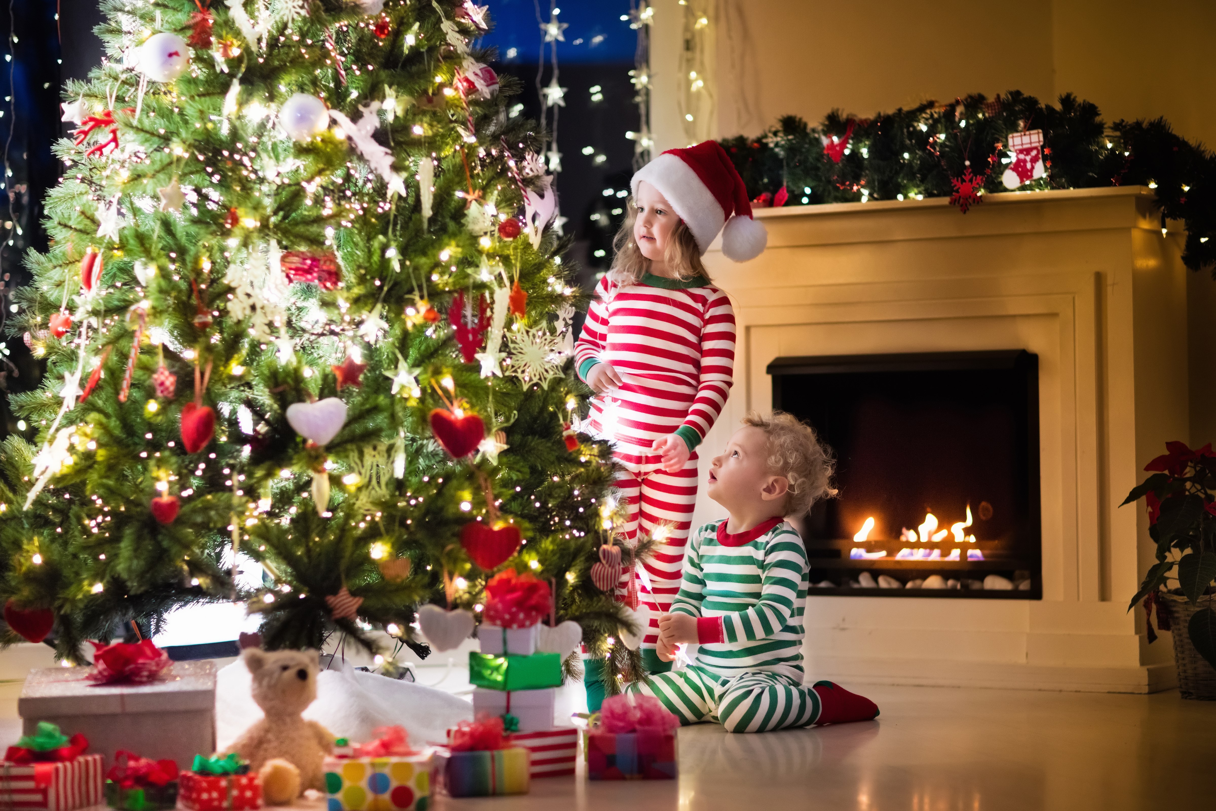 Children in pajamas by a Christmas tree and fireplace HD Wallpaper