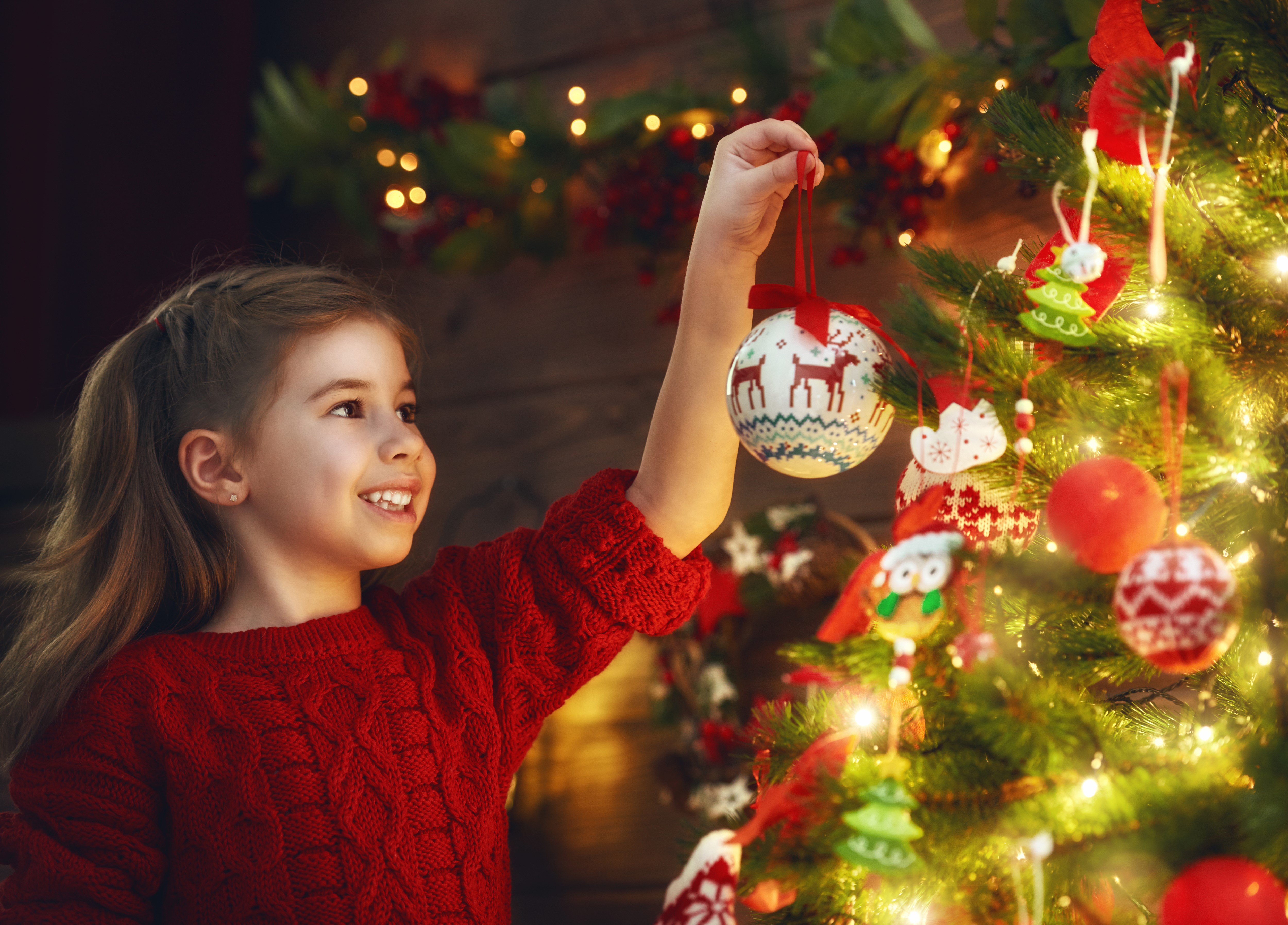 Girl decorating Christmas tree with ornaments HD Wallpaper
