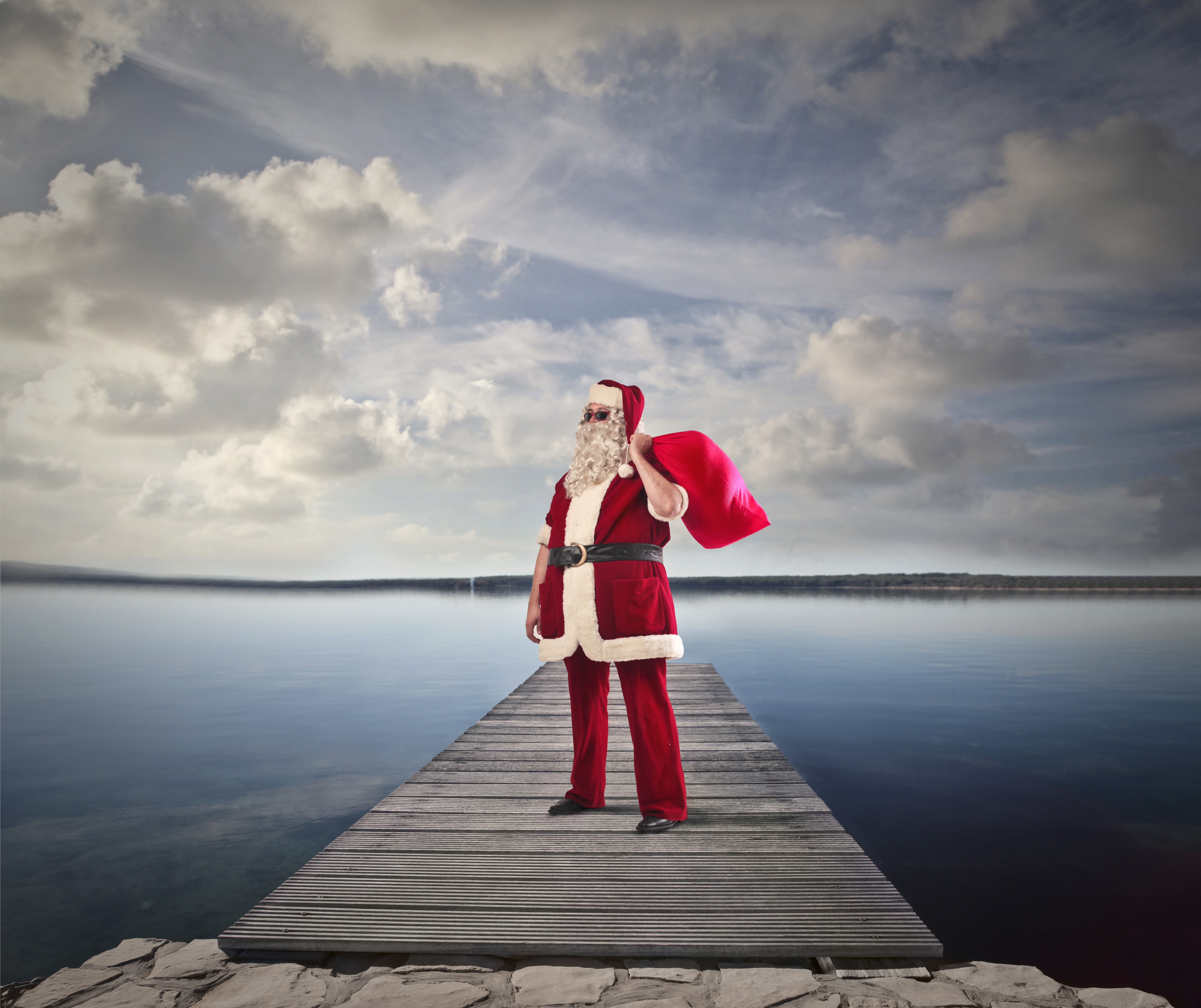 Santa Claus on a wooden pier with a gift bag HD Wallpaper