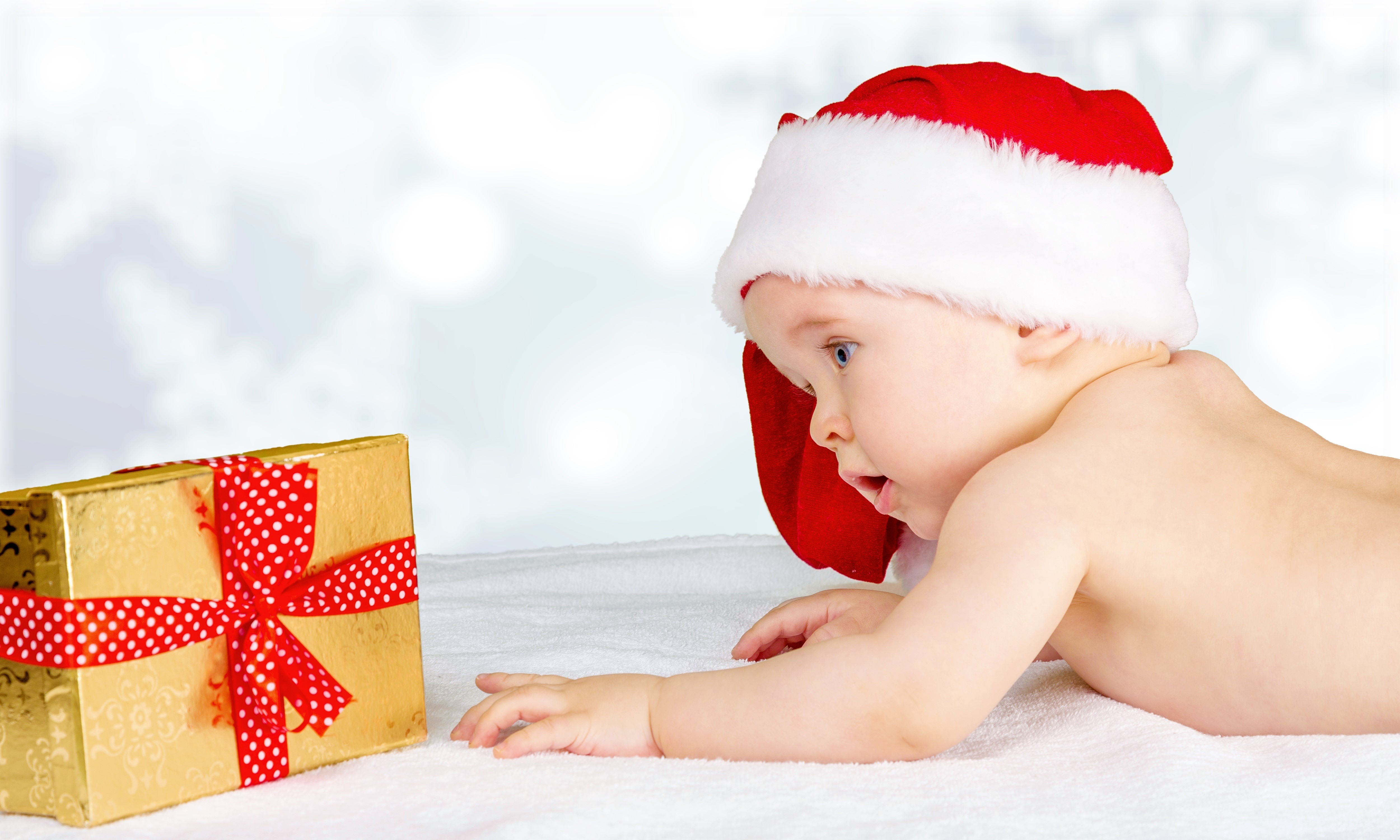 Baby in Santa hat looking at Christmas gift HD Wallpaper