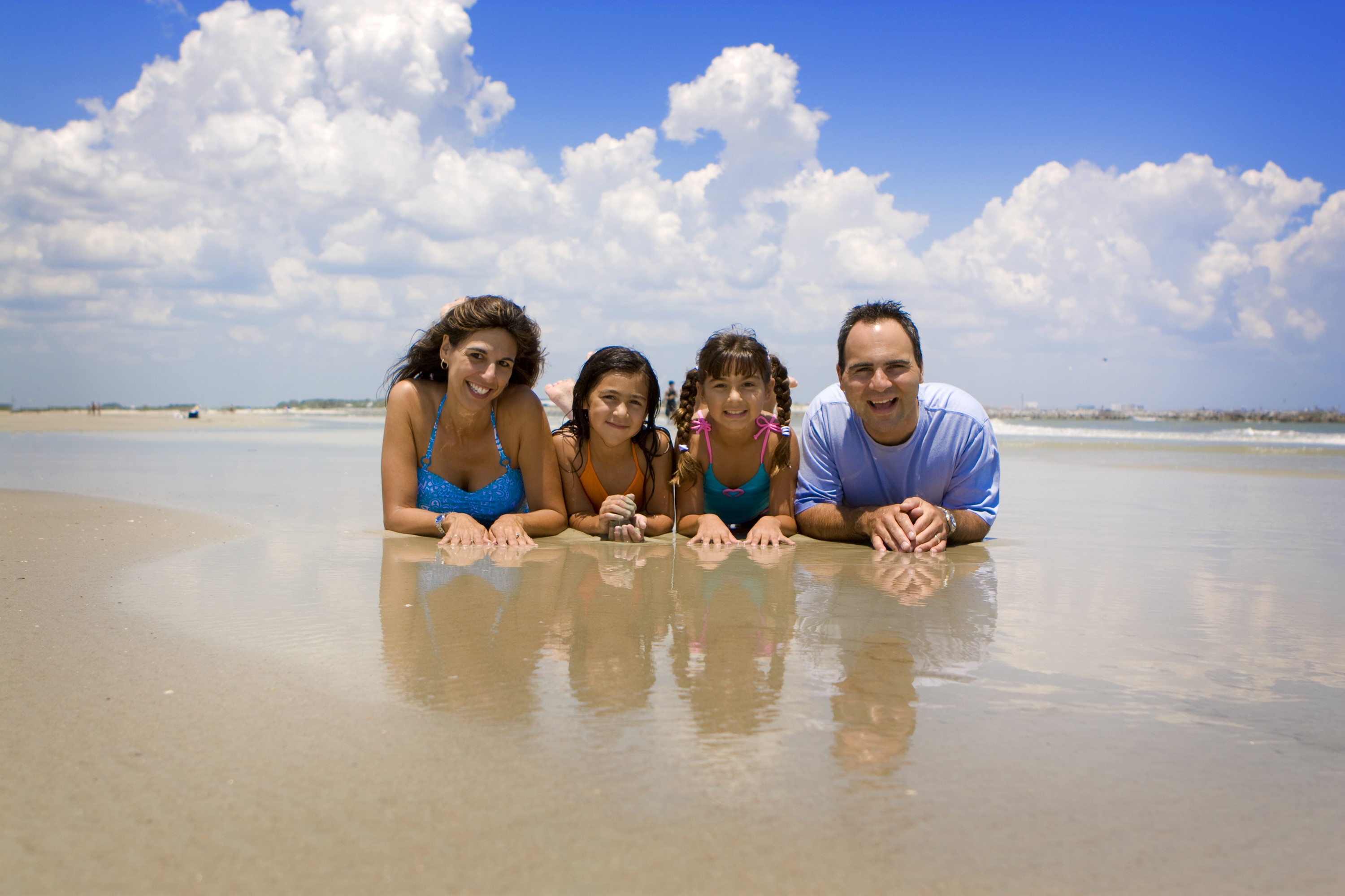 Family lying on a beach under a cloudy sky HD Wallpaper