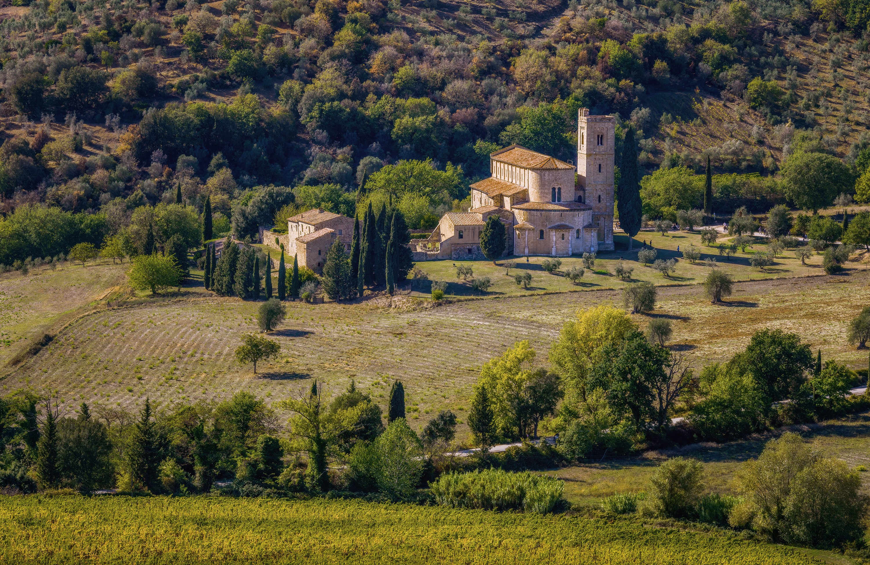 Abbey of Sant Antimo, Tuscany, Italy, with surrounding fields and trees HD Wallpaper