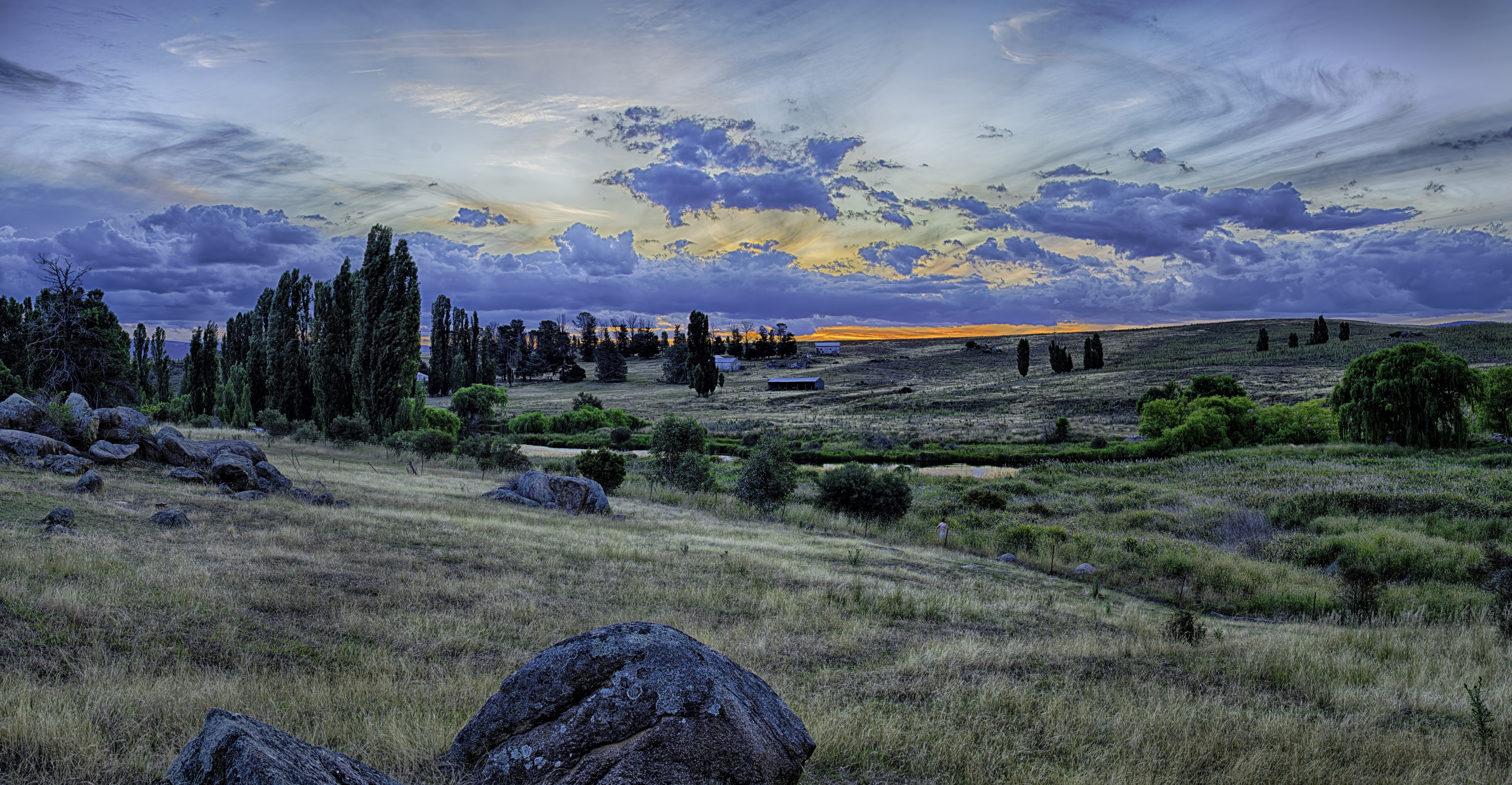Rural landscape with tall trees and rocks at sunset HD Wallpaper