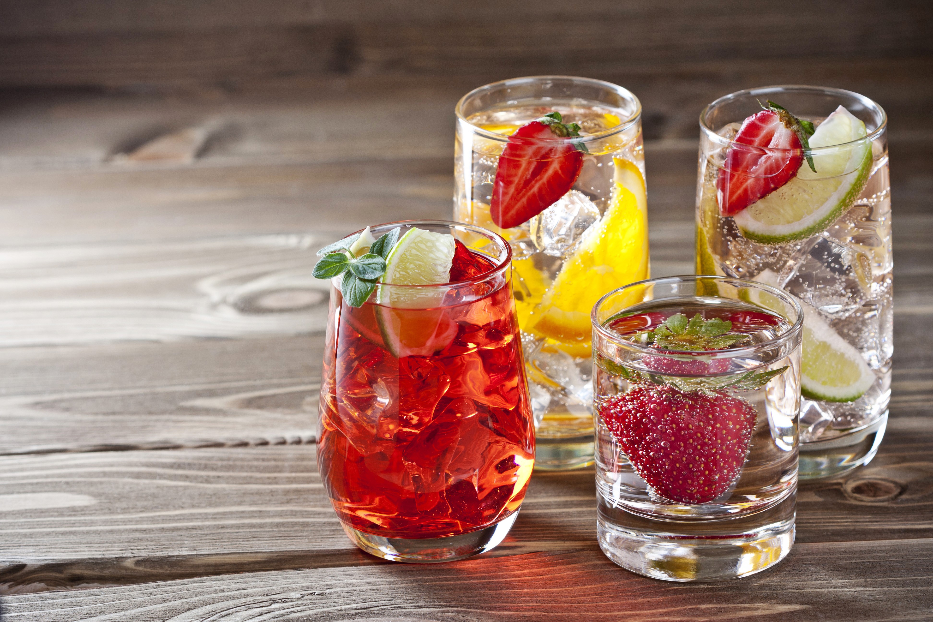 Four fruit-infused drinks on wooden planks HD Wallpaper
