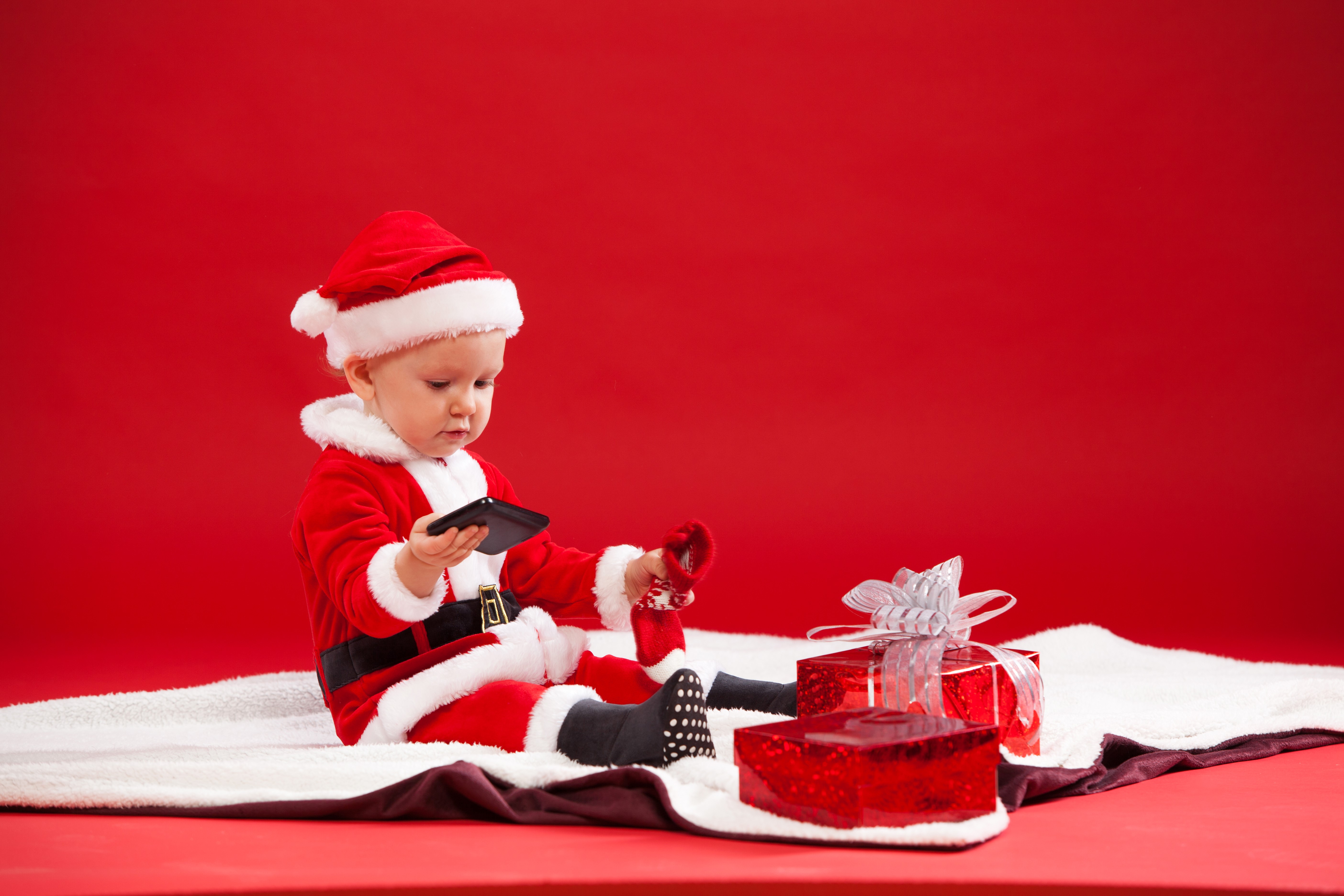 Baby in Santa costume with gifts and phone HD Wallpaper