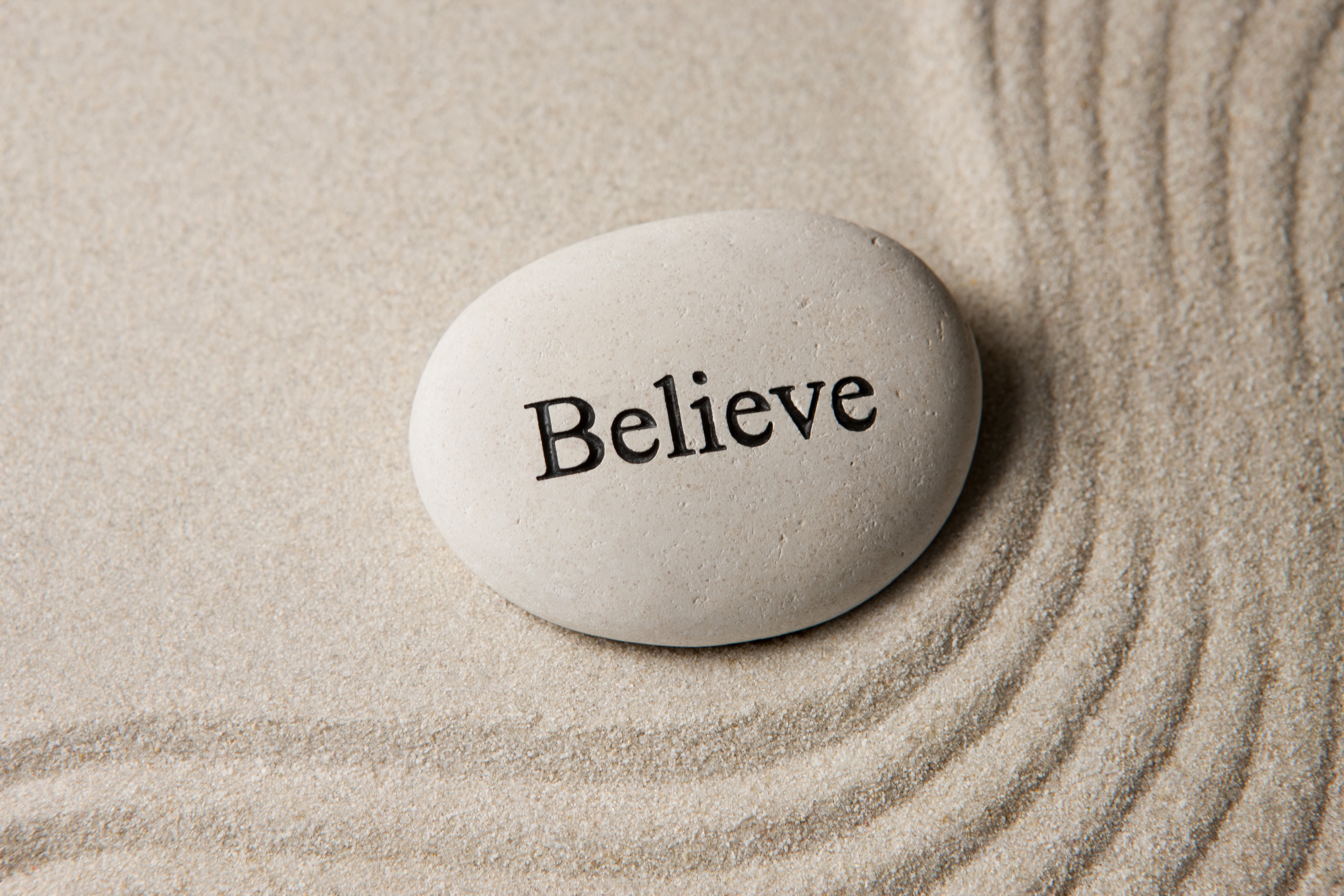 Stone with the word Believe on sand HD Wallpaper