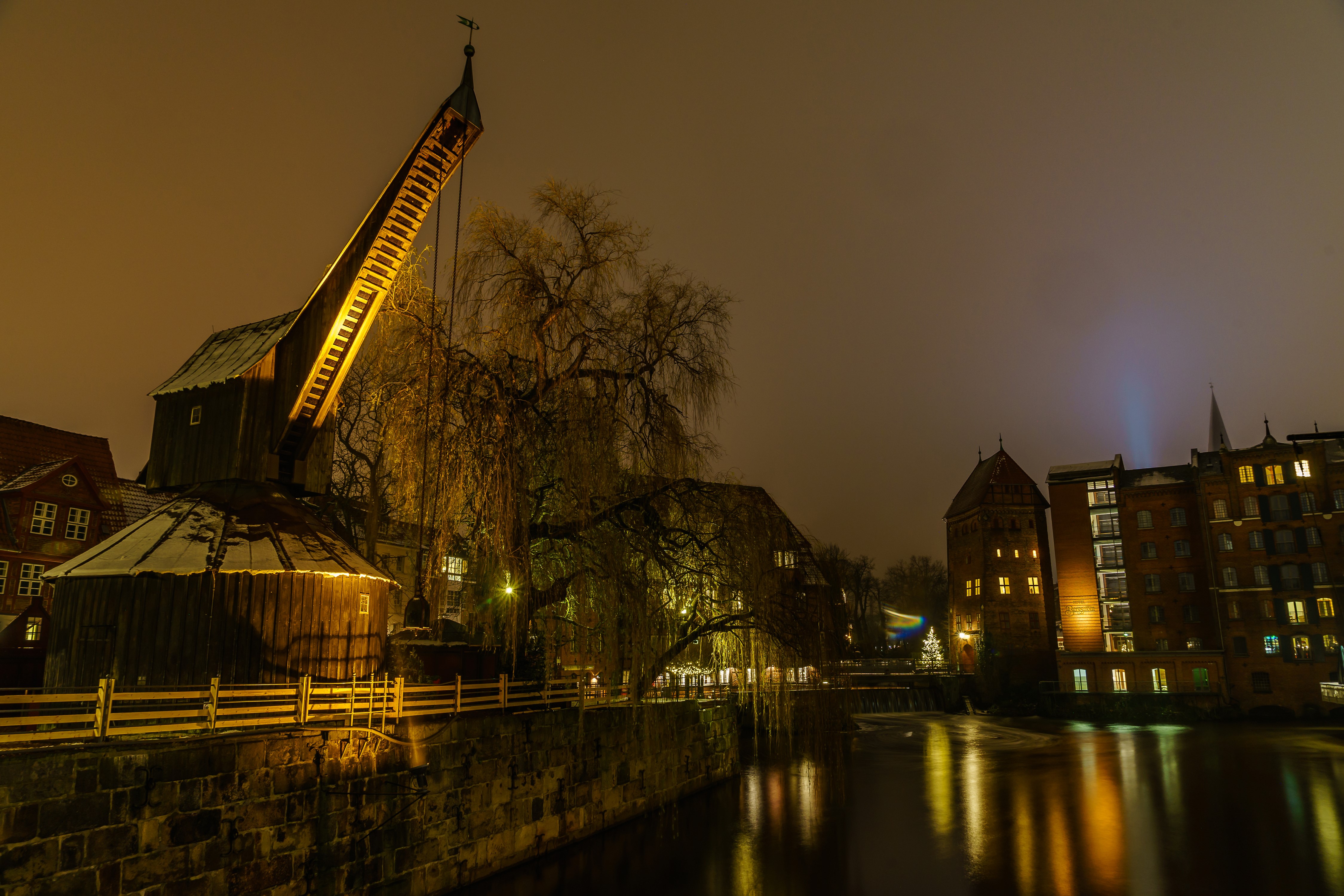 Crane and buildings by river at night in Luneburg, Germany HD Wallpaper