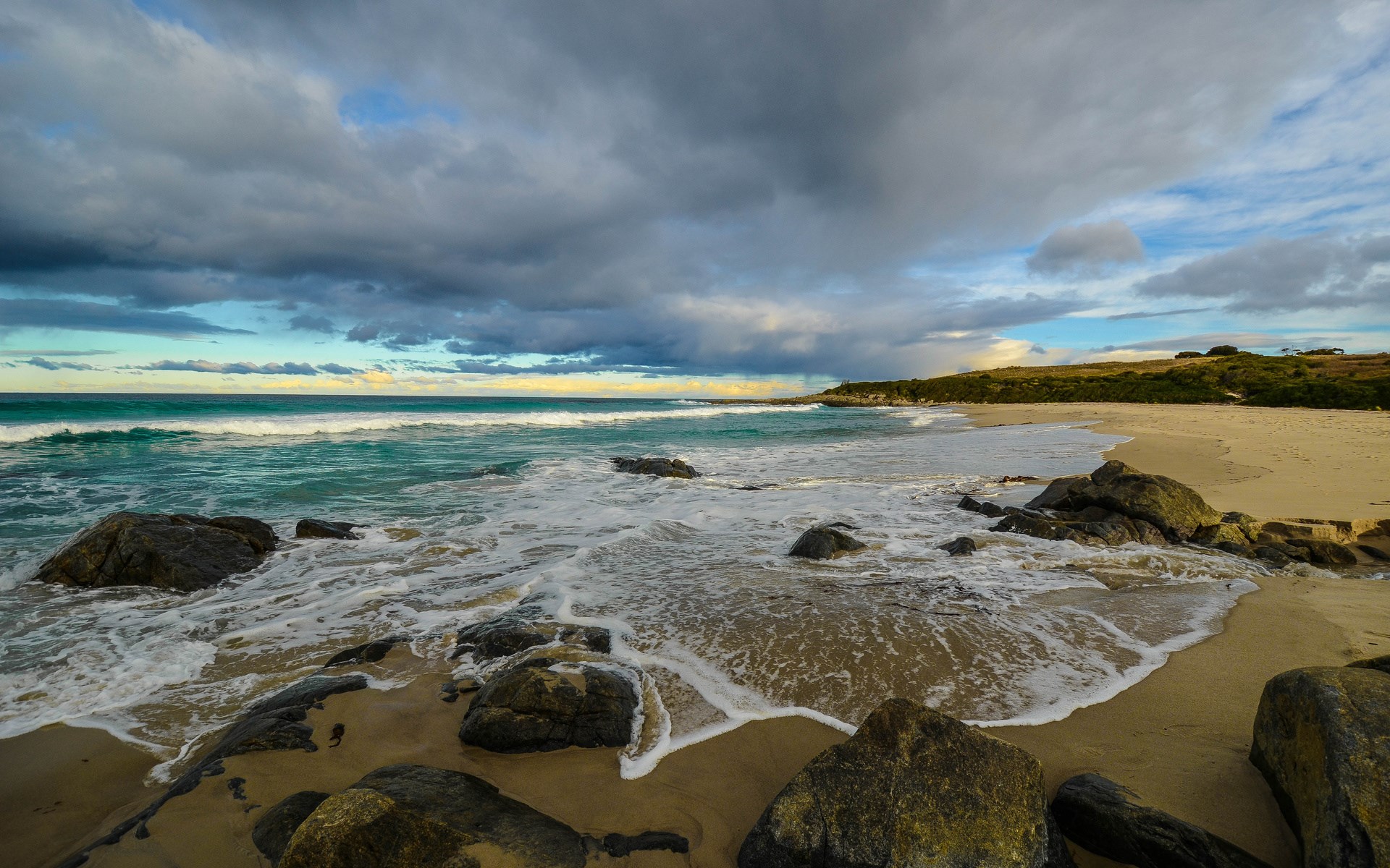 Waves crashing on a rocky beach under cloudy skies HD Wallpaper