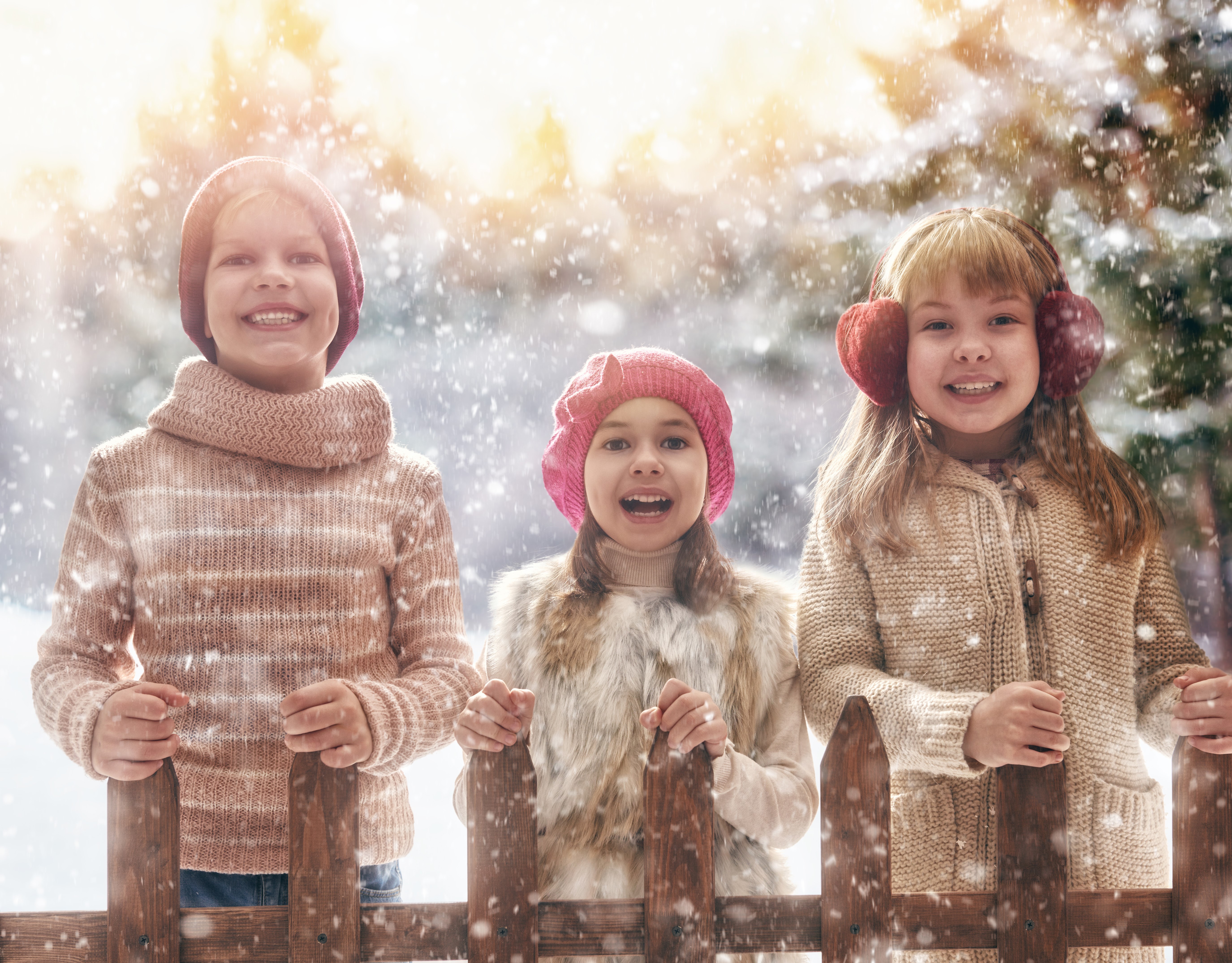 Three smiling children in winter hats and sweaters in the snow HD Wallpaper