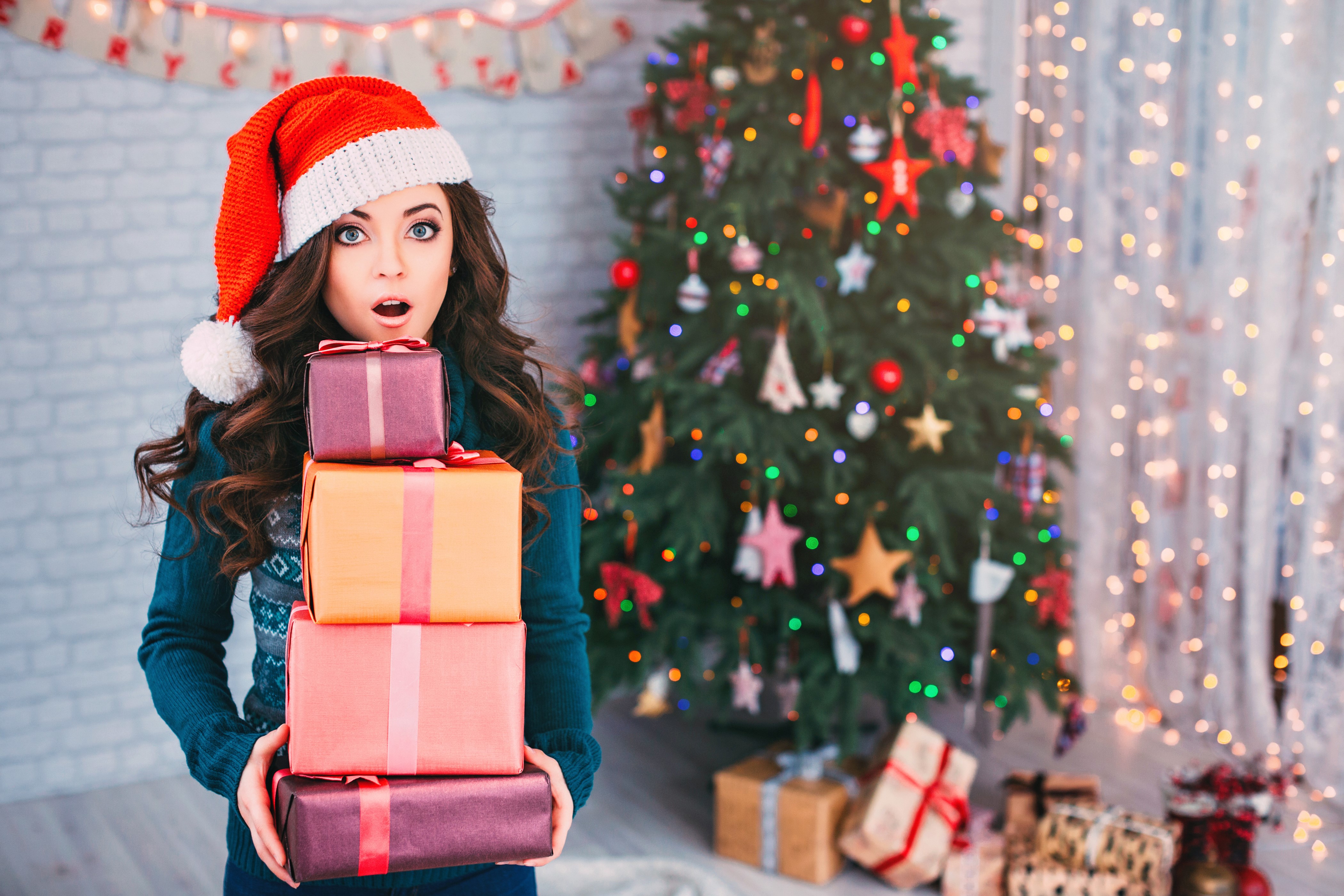 Woman in Santa hat holding Christmas gifts HD Wallpaper