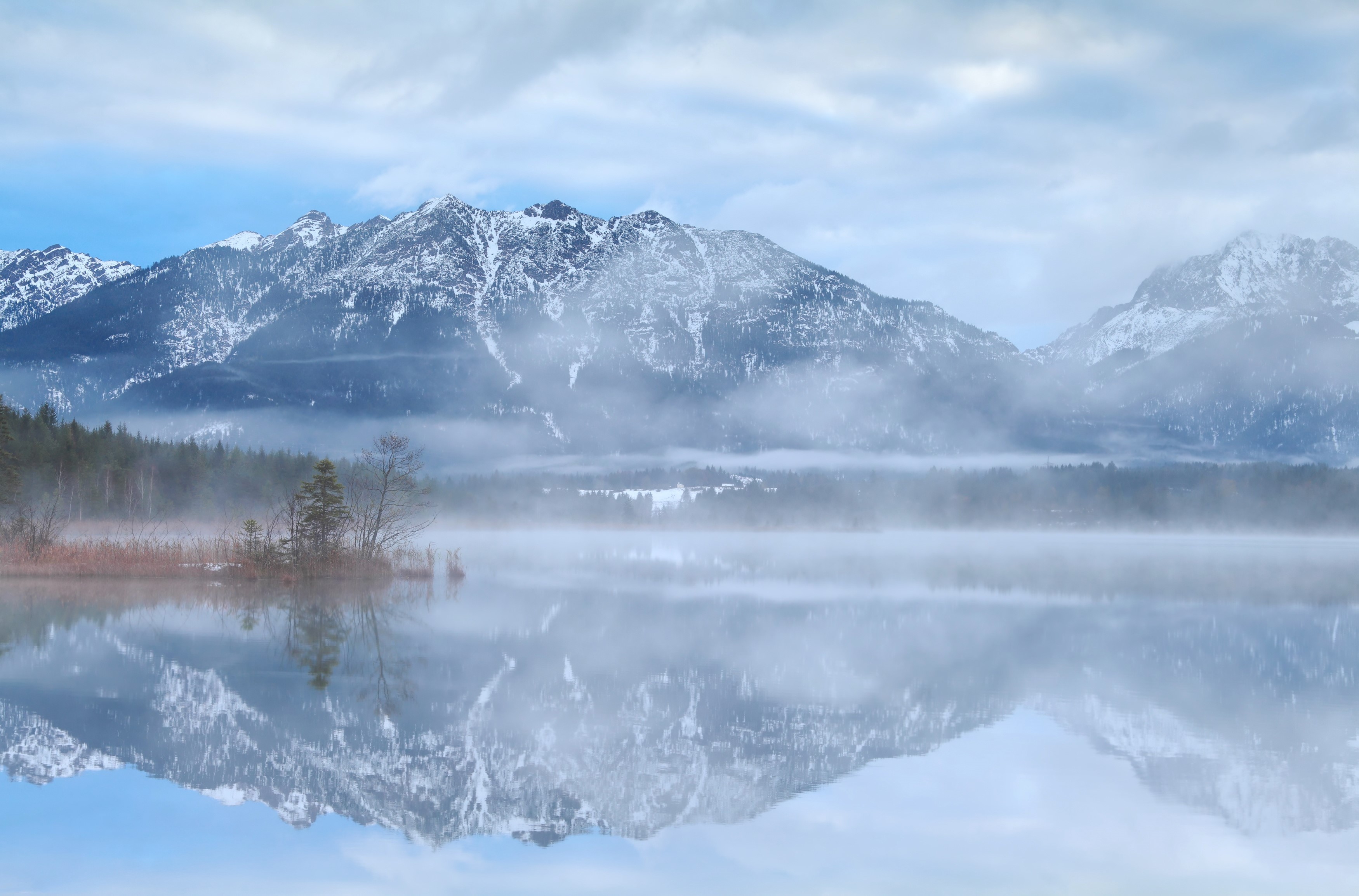 Misty lake reflecting snow-capped mountains in Bavaria HD Wallpaper