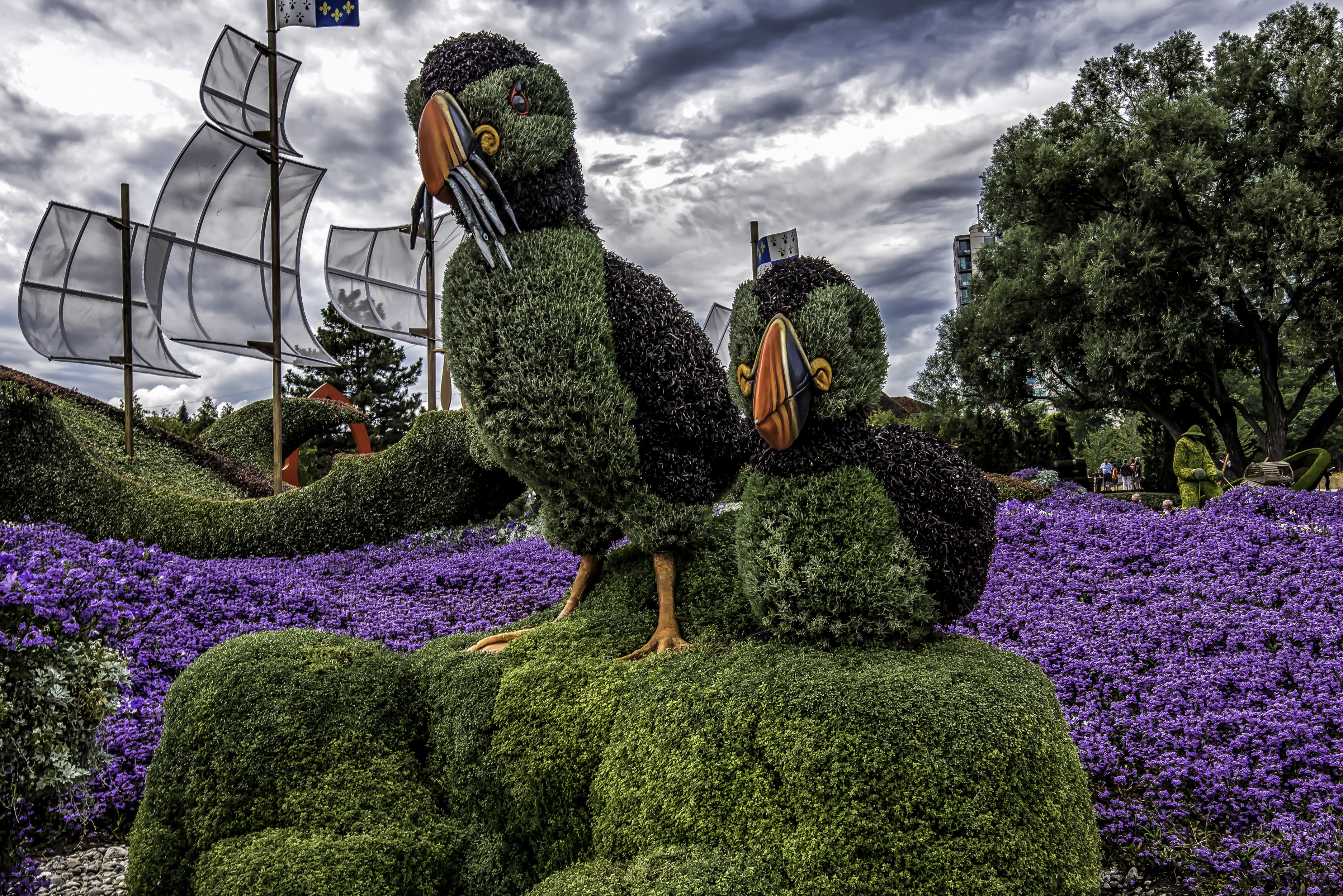 Topiary birds and ship in a garden with purple flowers HD Wallpaper
