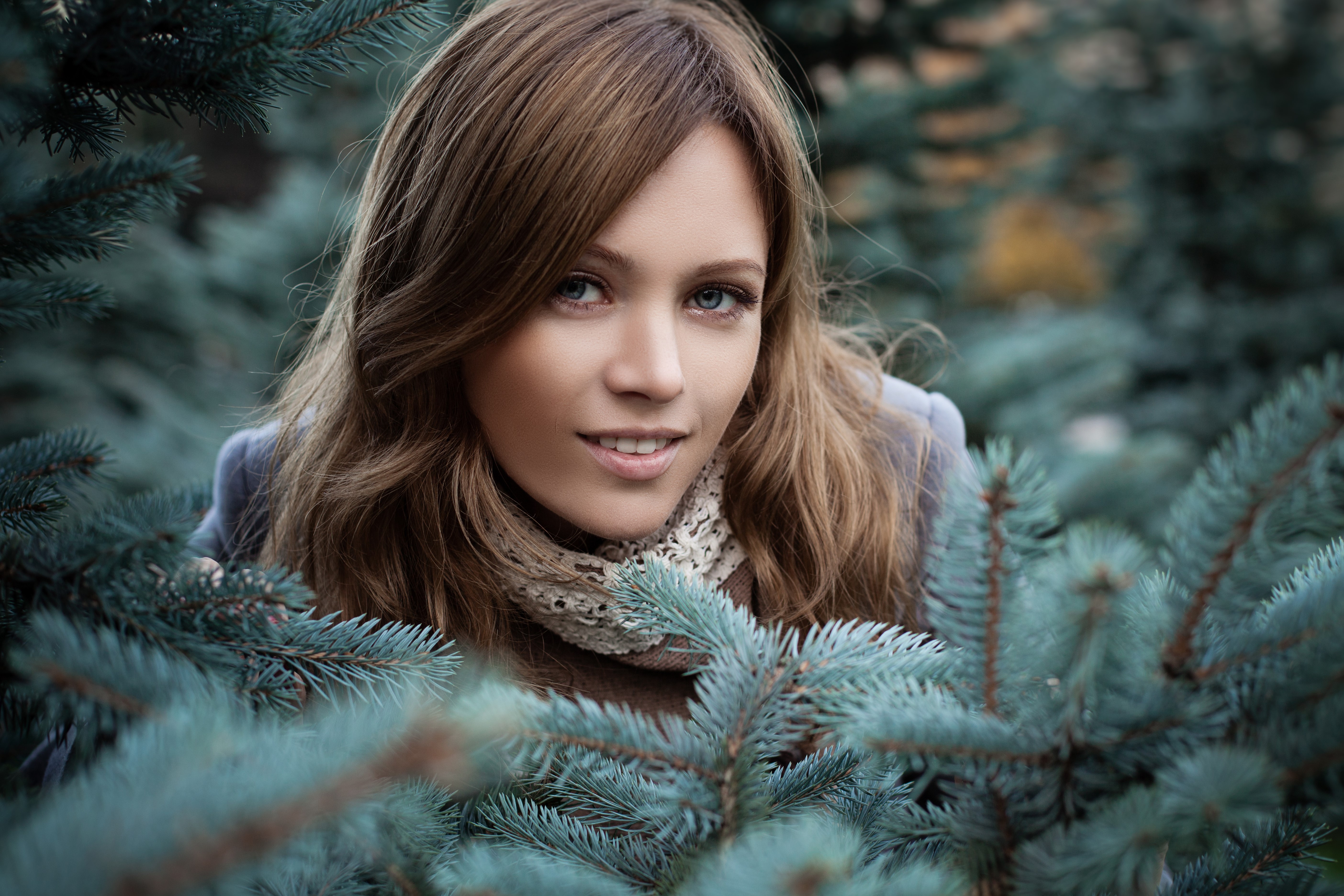 Woman peeking through pine branches HD Wallpaper