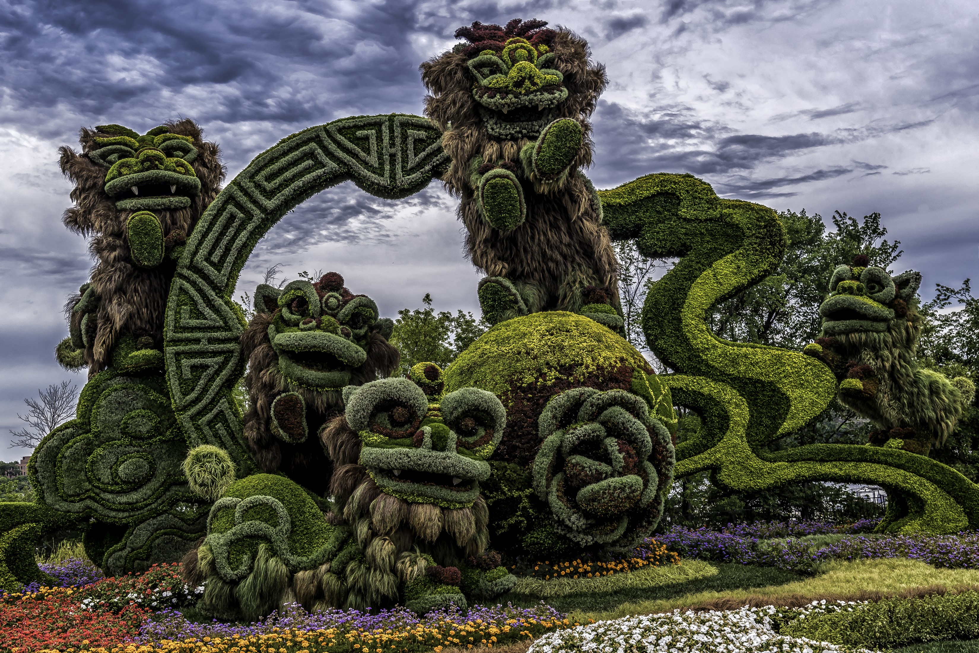 Topiary sculptures of lions and dragons in a park HD Wallpaper