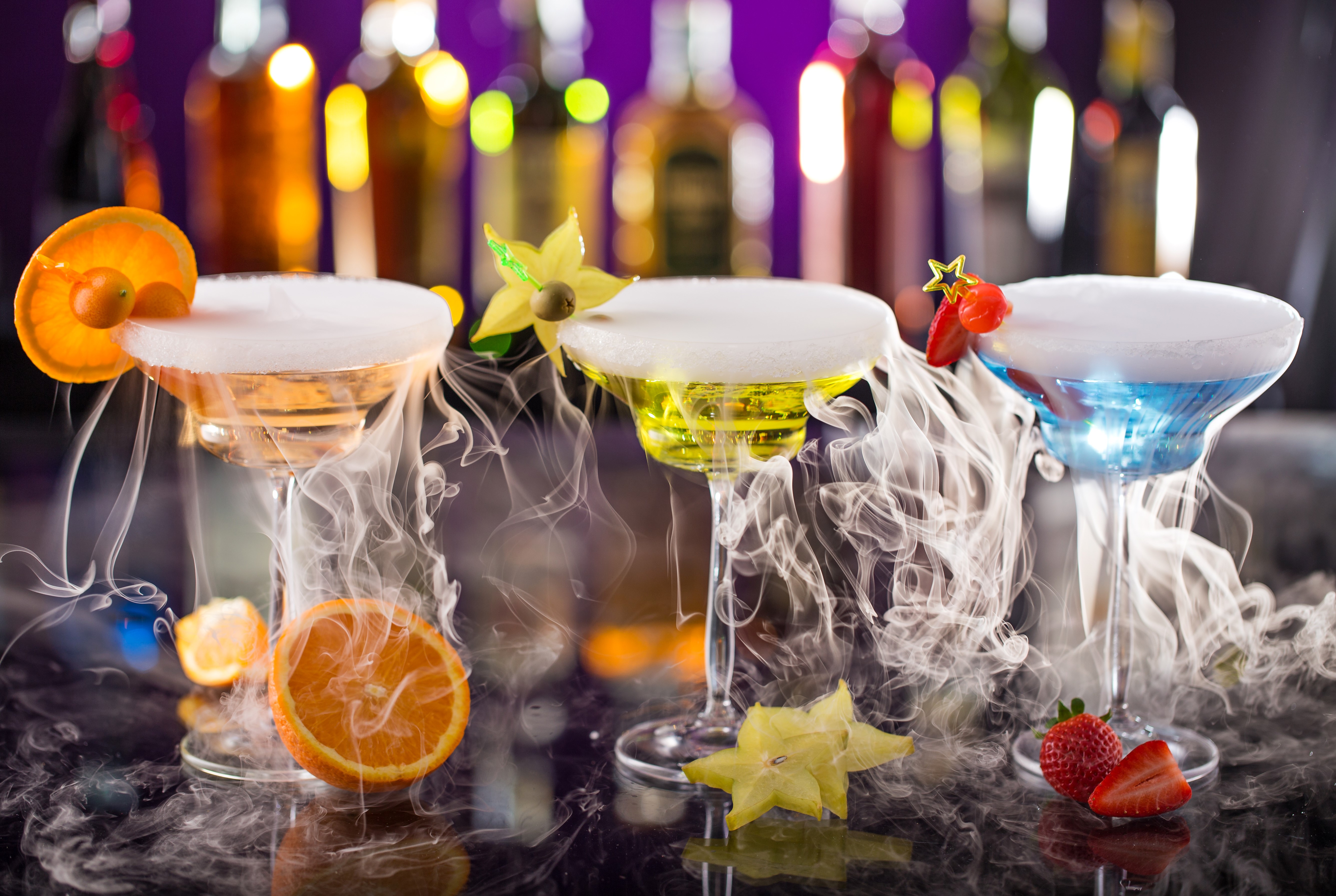 Three cocktails with smoke and fruit garnishes HD Wallpaper