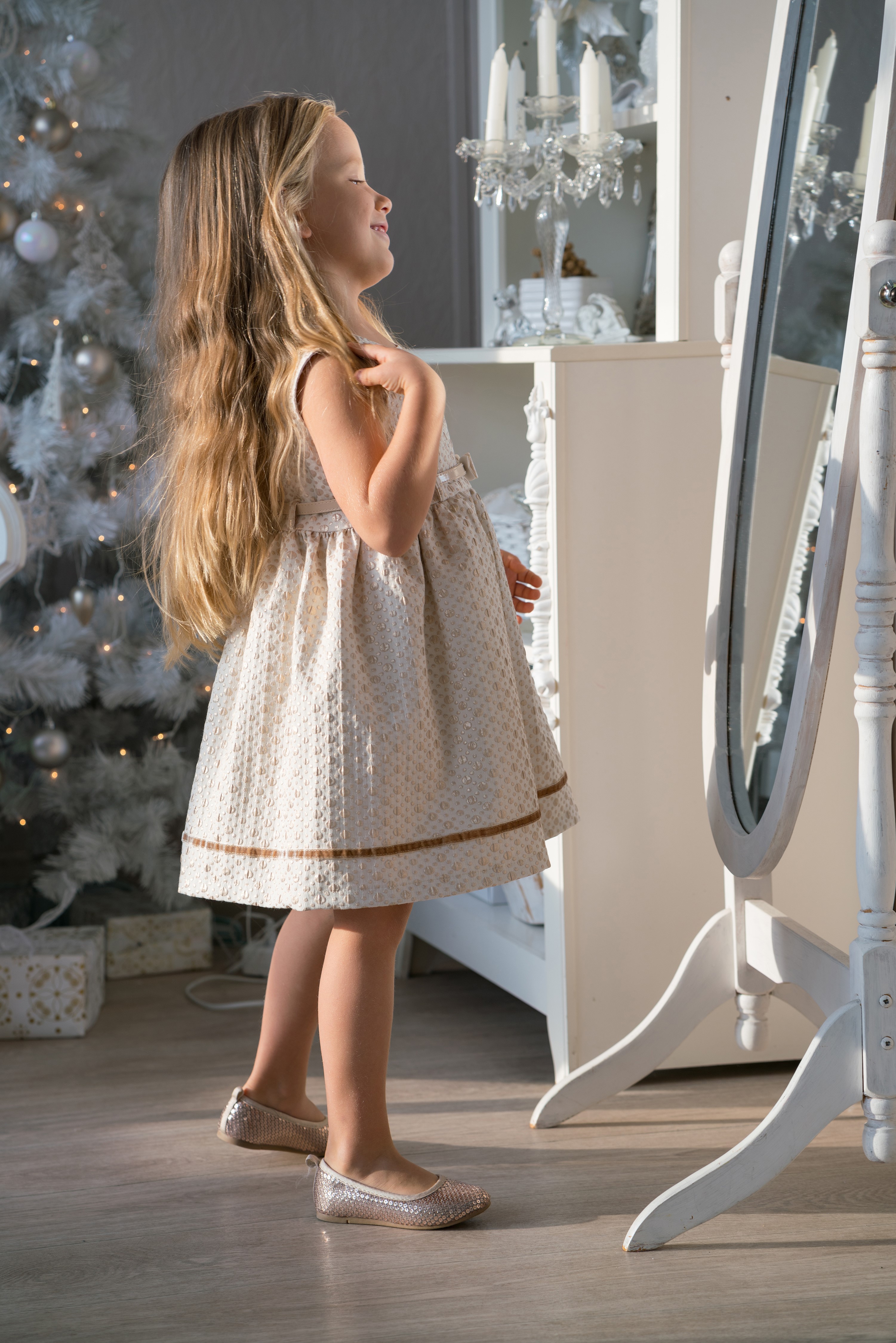 Girl in a dress looking in a mirror near a Christmas tree HD Phone Wallpaper