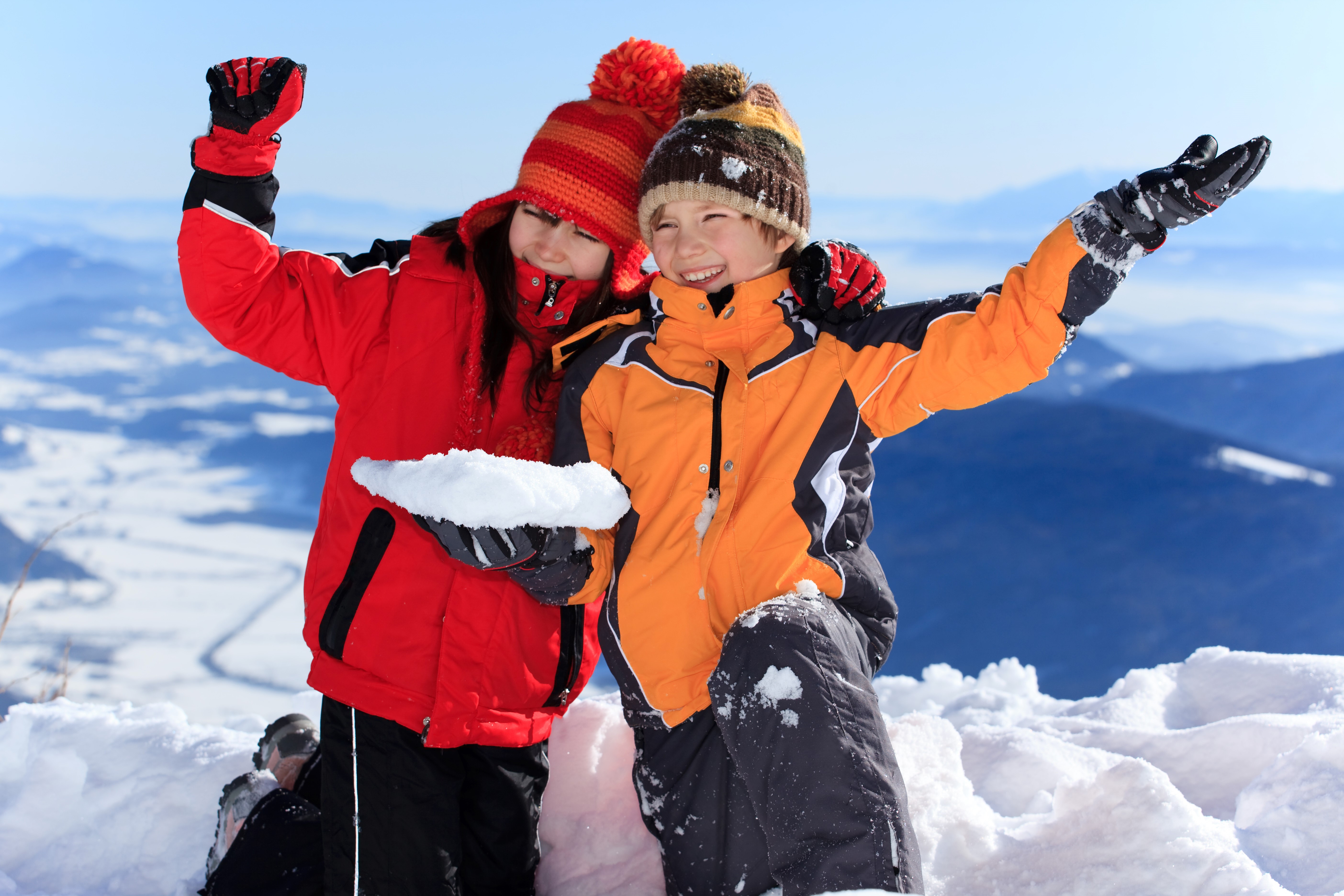 Two children in winter jackets holding snow HD Wallpaper