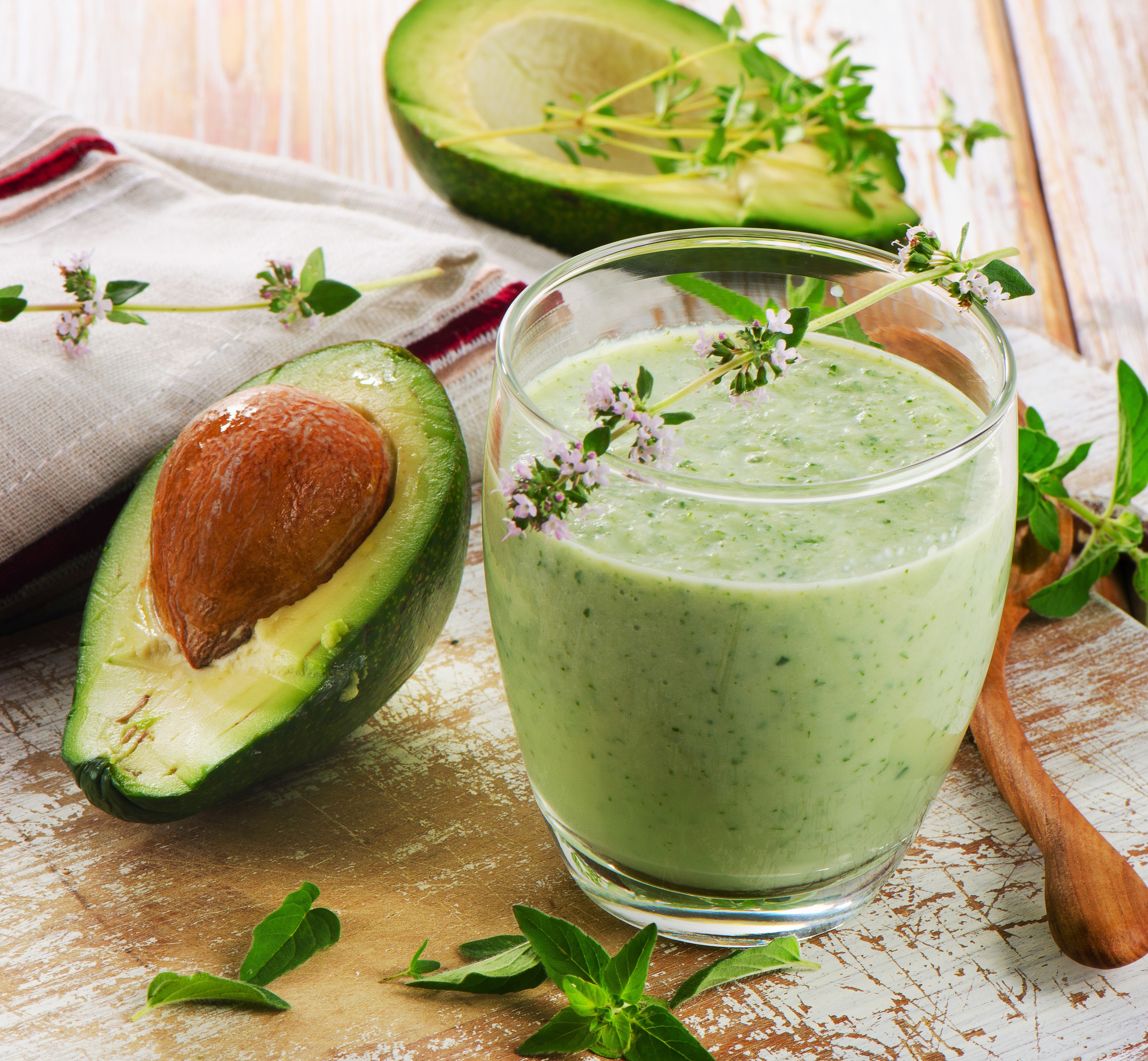 Avocado smoothie in a glass with fresh avocado halves HD Wallpaper