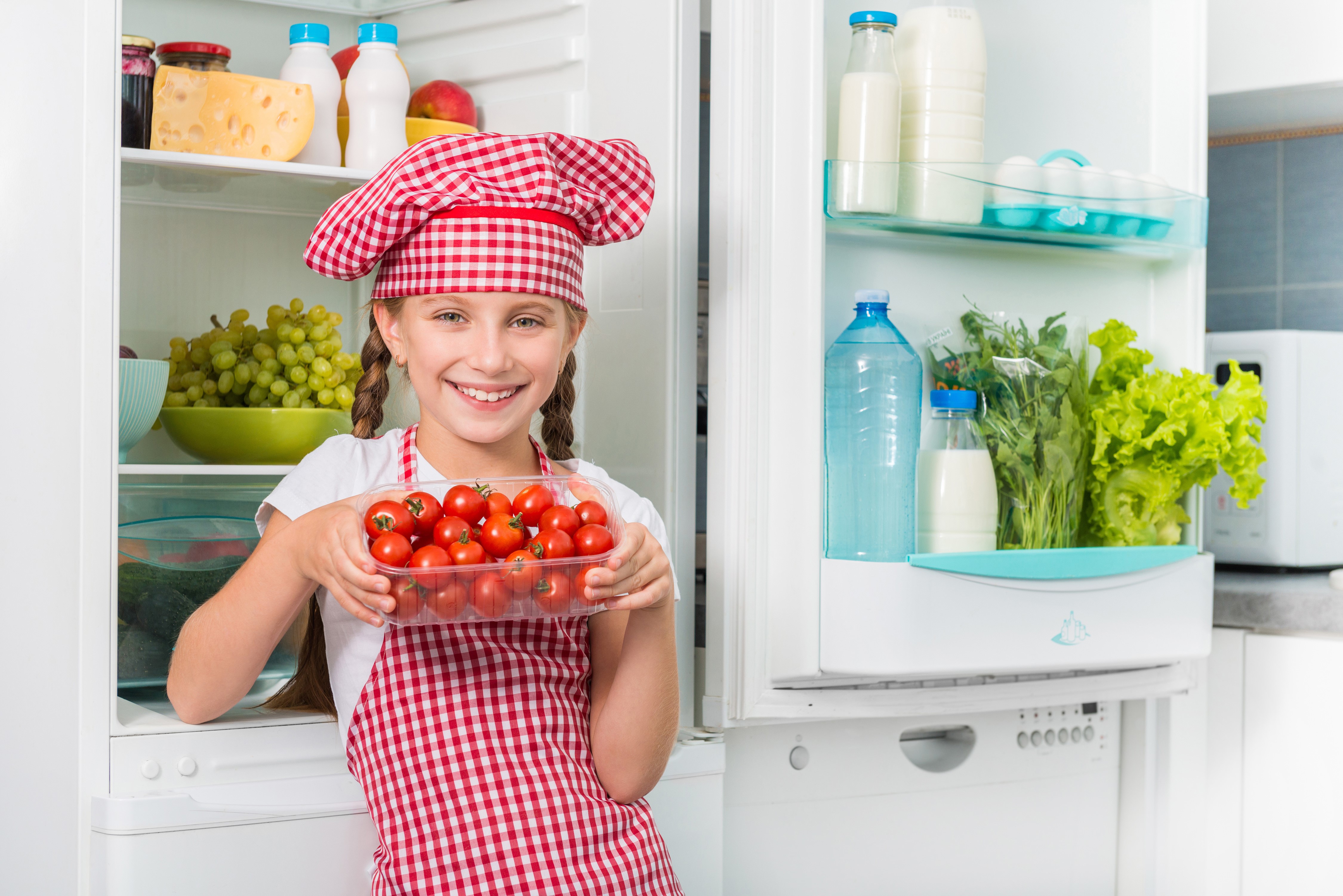 Girl in chef hat holding tomatoes in refrigerator HD Wallpaper