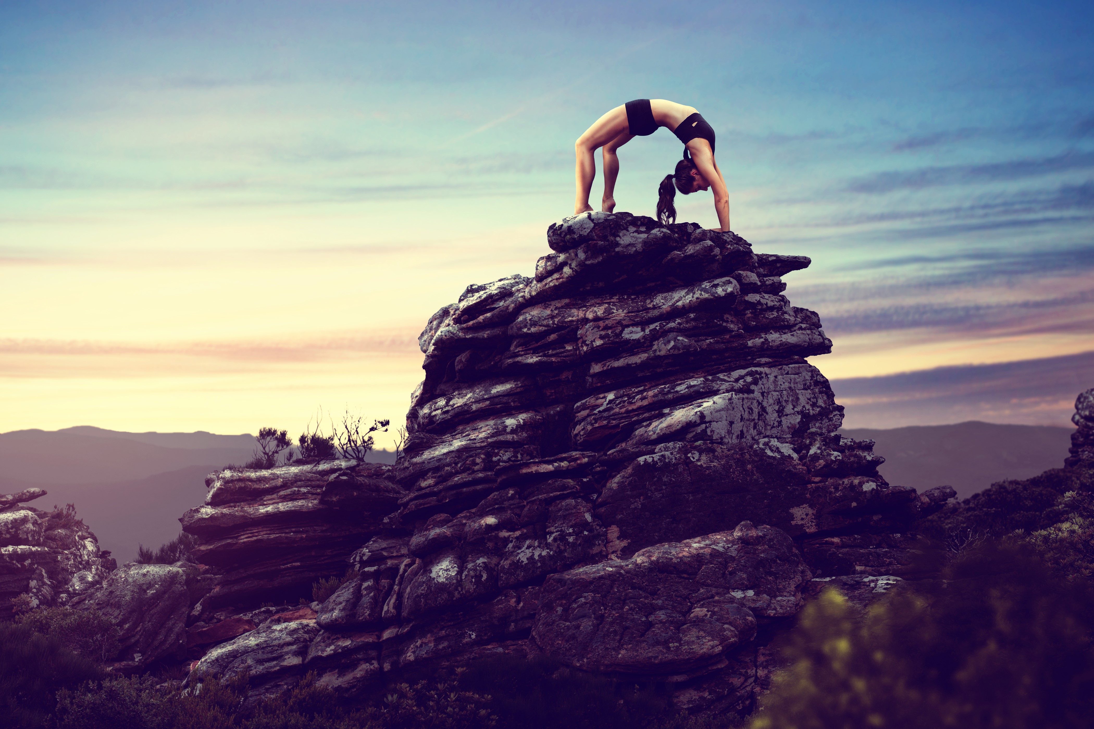Woman doing yoga bridge pose on a rocky mountain peak HD Wallpaper