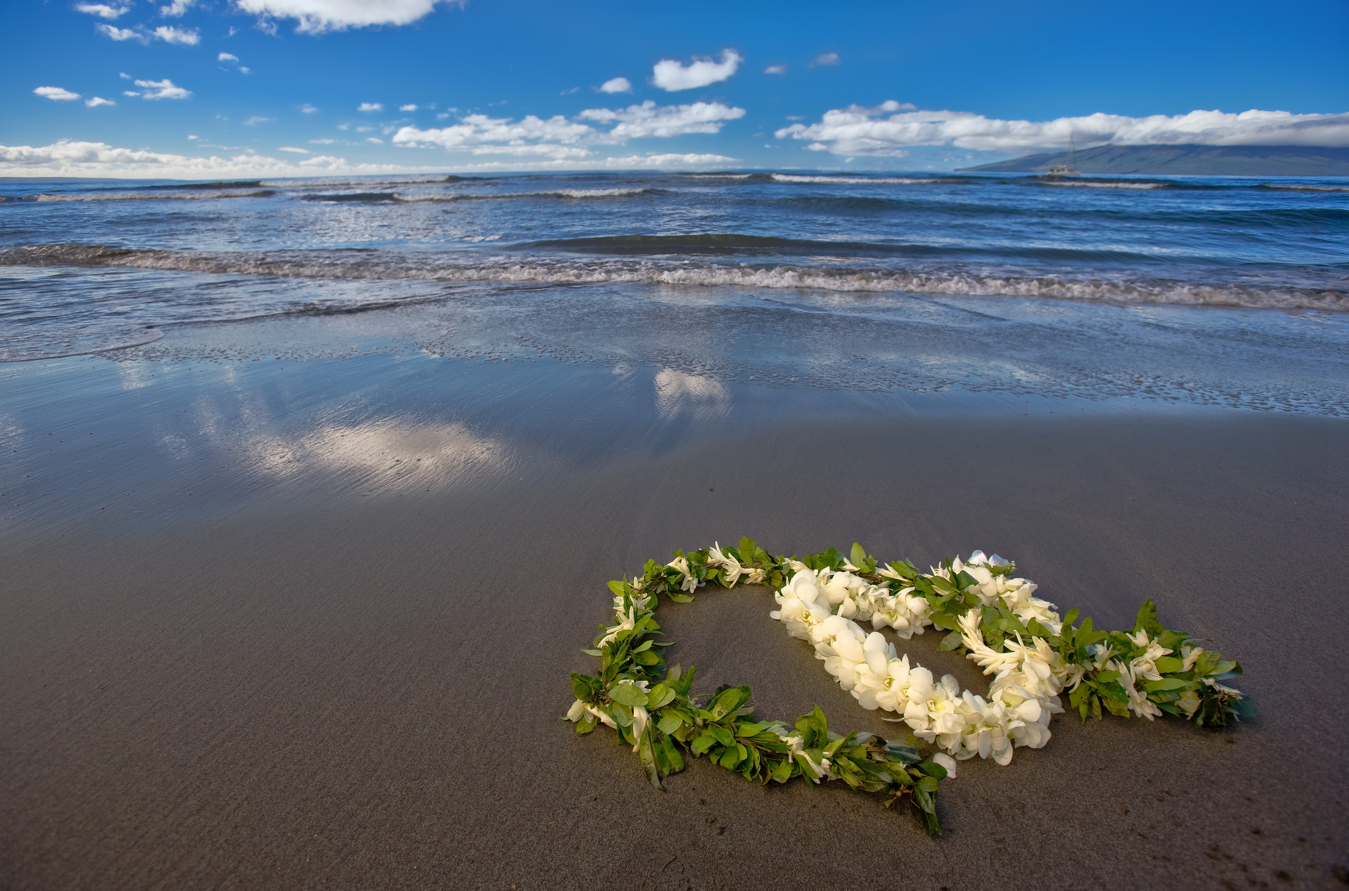 Heart-shaped lei on a beach with ocean waves HD Wallpaper