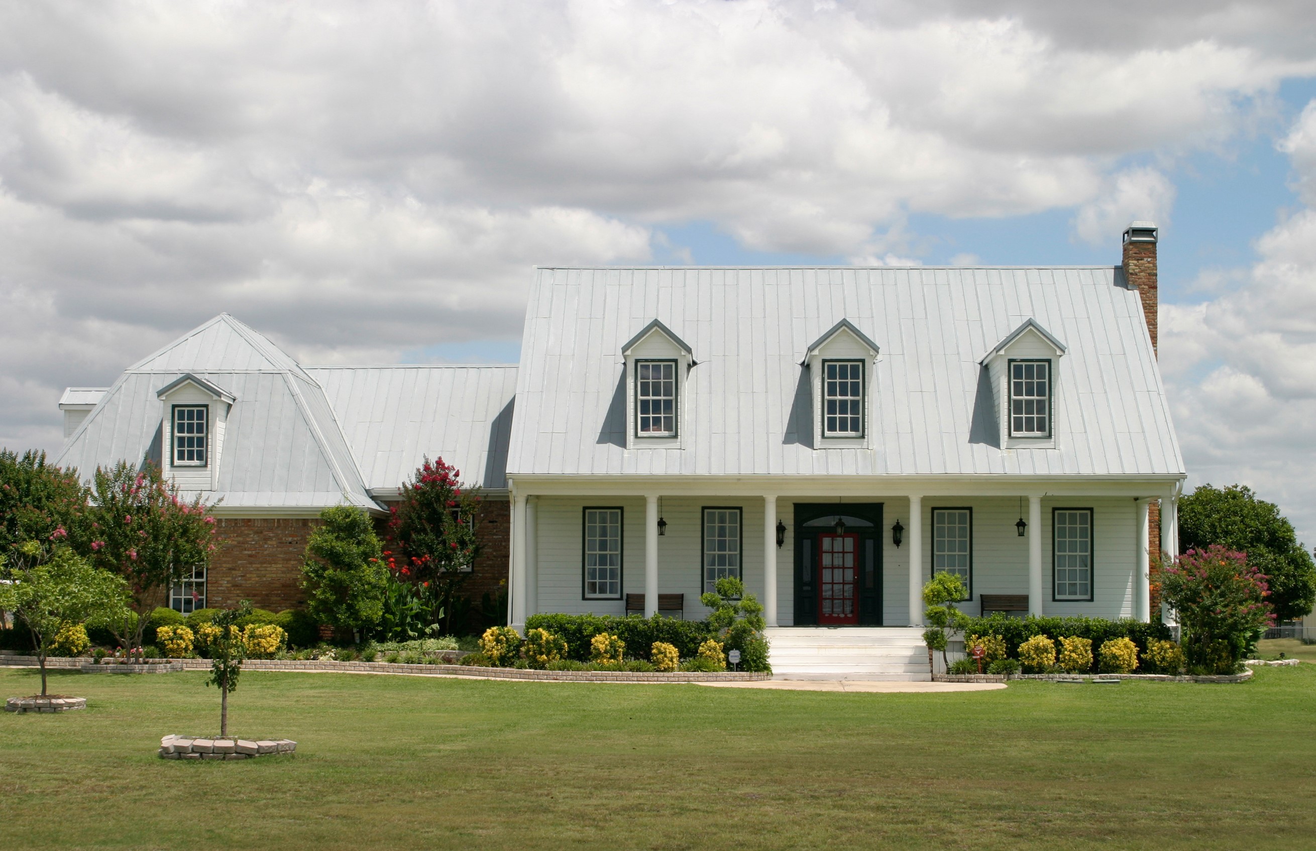 Large white house with metal roof and dormer windows HD Wallpaper